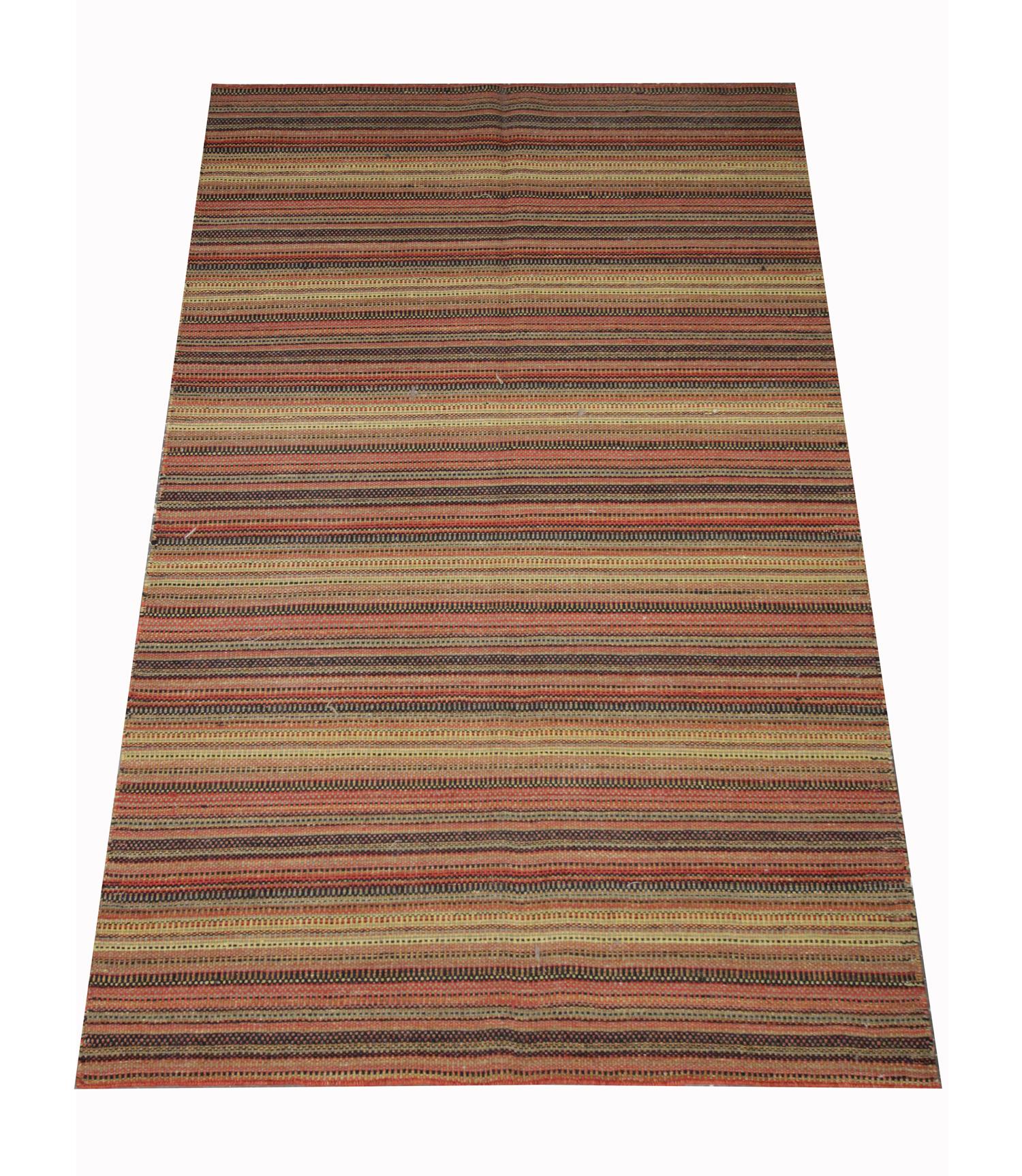 This bold area rug is a flat woven kilim, woven by hand in the early 21st century. The design features a simple stripe pattern woven in accents of beige, red, brown and black. The colour and the design make this piece the perfect accent rug for both