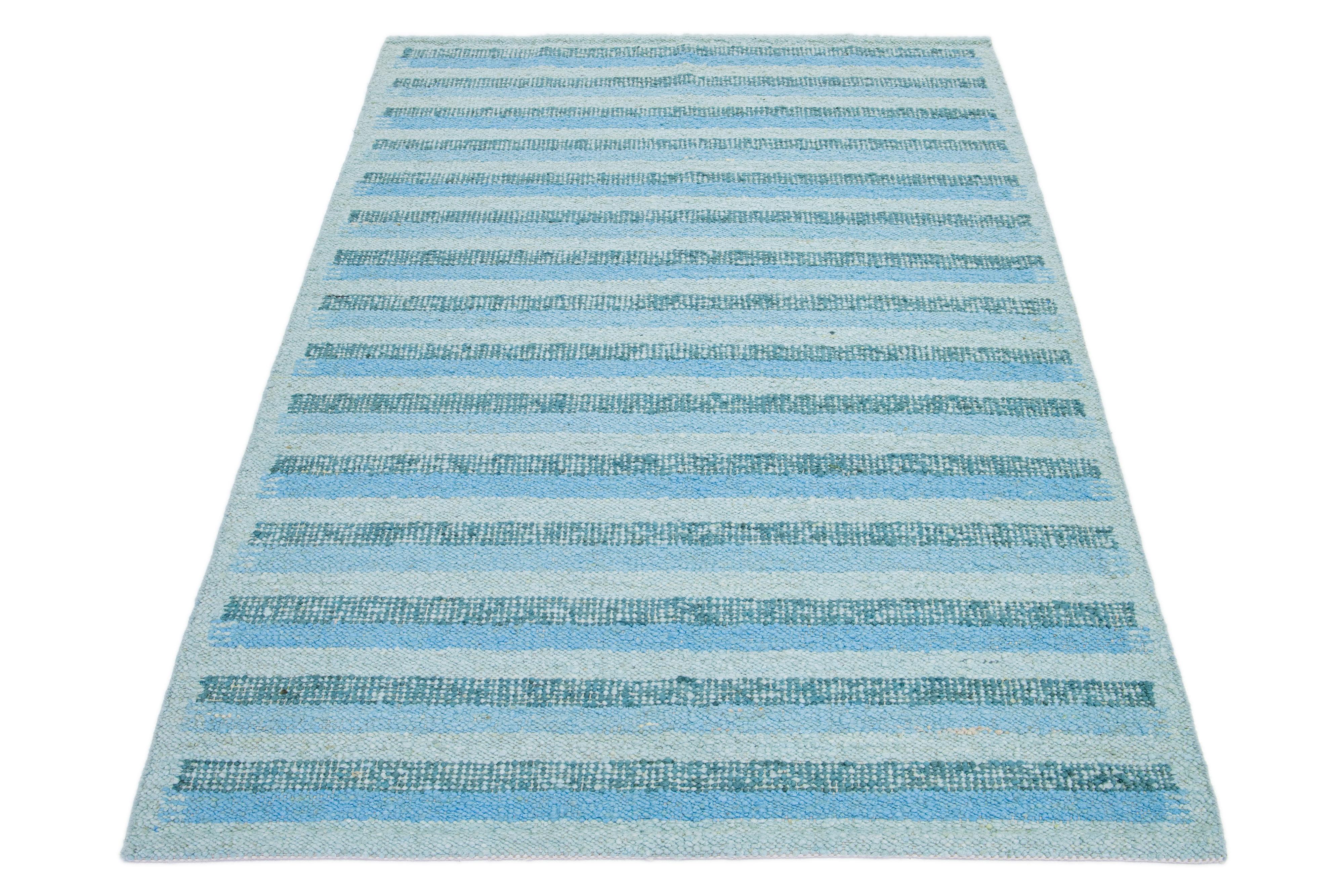 This flatweave rug features a chic contemporary Swedish design with a green field color. It has a striped pattern throughout the rug in light blue shades.

 This rug measures 6'2