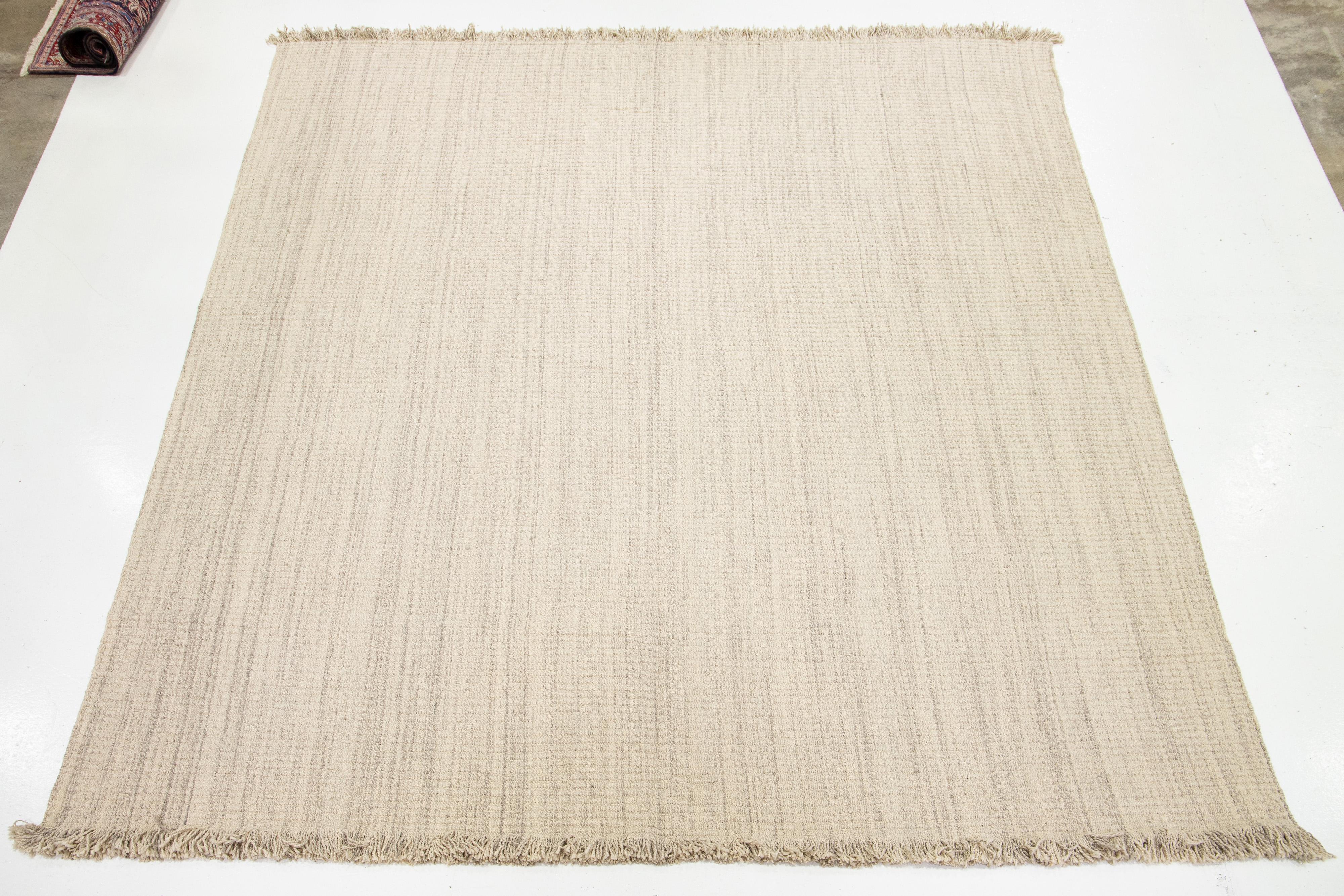Dieser flachgewebte Naturteppich zeichnet sich durch ein modernes Dhurrie-Design aus, das sich durch eine beigefarbene Grundfarbe und stilvolle graue Streifen auszeichnet. Der Teppich ist elegant mit schönen Fransen verarbeitet.

 Dieser Teppich