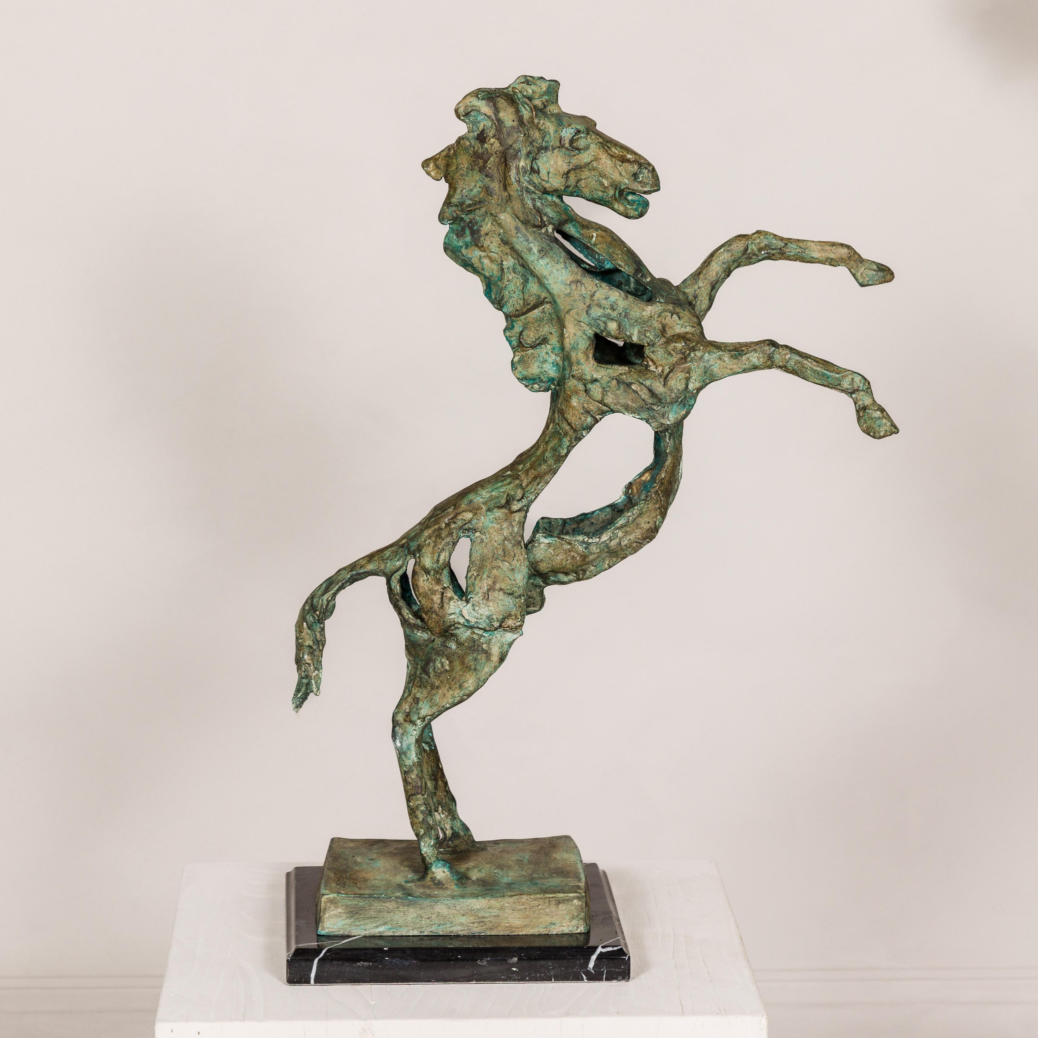 A Modern style bronze tabletop horse sculpture with verdigris finish and black veined marble base. Channeling the spirit of equestrian majesty with a contemporary twist, this Modern style bronze tabletop horse sculpture emerges as an artful