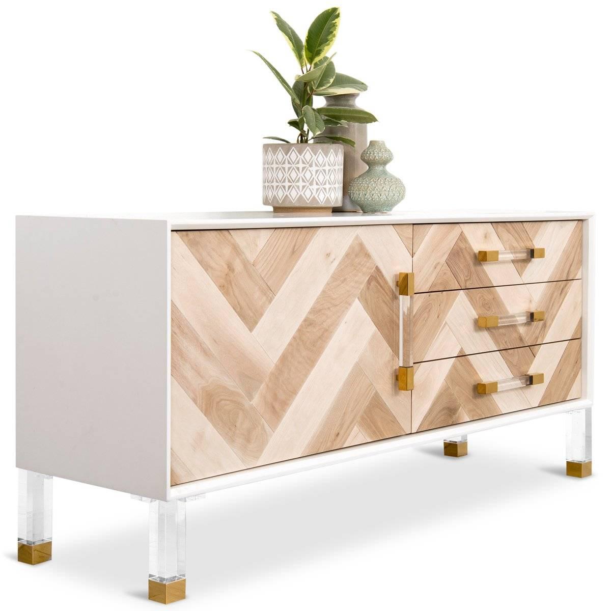 The Corfu one door three-drawer credenza is perfect for any spaces, with its walnut door face. This one here comes with a white case finish, brass and Lucite legs and the wood pieces placed on the doors create a large herringbone effect.