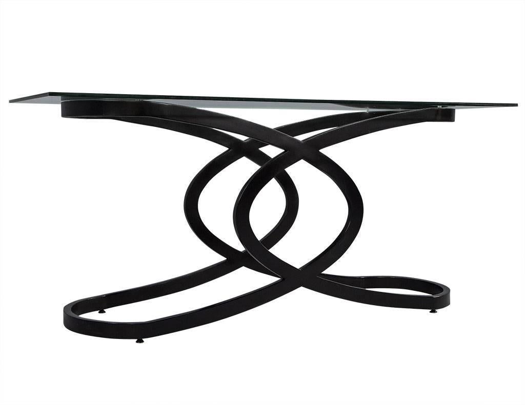 This geometric base, modern console table in black is an instant attention grabber for your living room. Made from wood, the geometric-inspired base offers sturdy support to this console table while enhancing its appeal. The glass tabletop