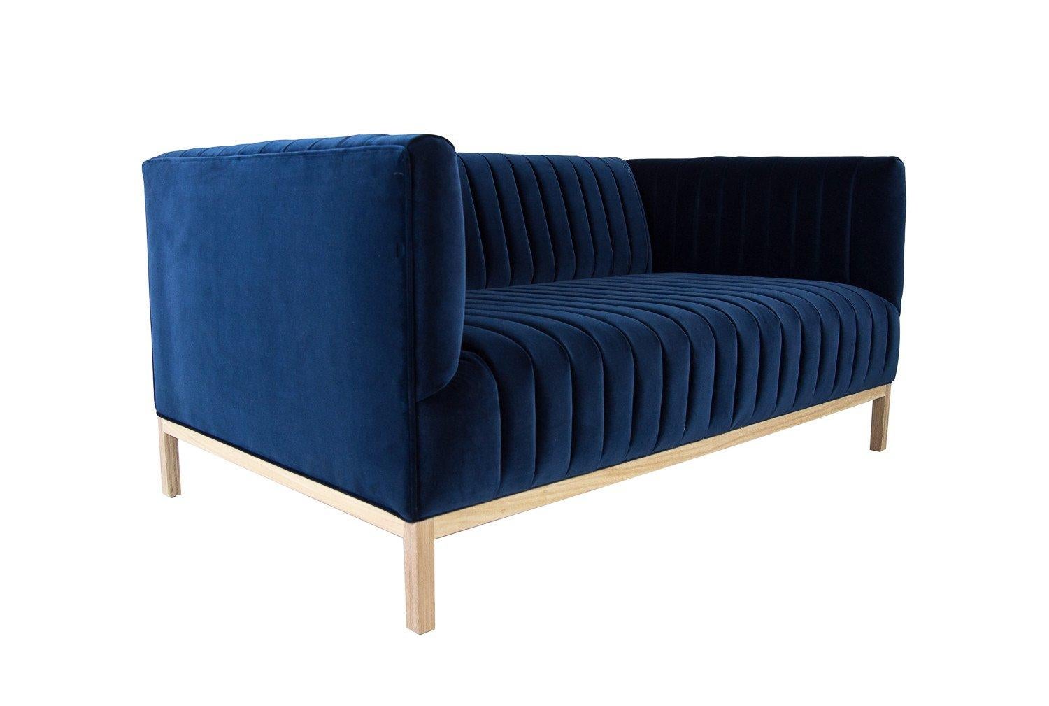 The Manhattan sofa epitomizes the modern loft lifestyle of the 21st century New Yorker. An economy of style and comfort come together in this beautiful, long arm tufted sofa, shown here in Como Indigo Velvet with a solid bleached walnut base. Bring