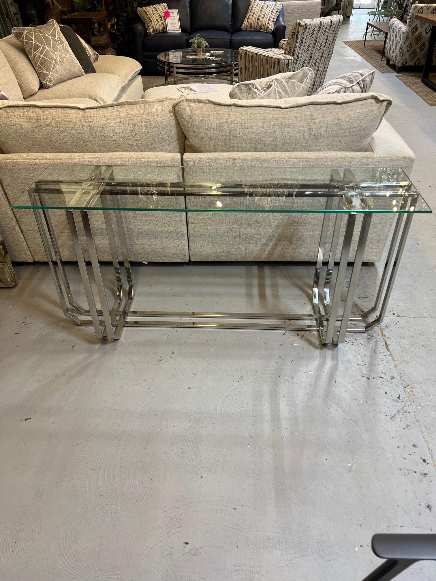 Modern style nickel console table with a clear glass top. A perfect piece for a contemporary design or to add a modern touch. A good piece to use behind a sofa or use in an entrance or dining room. Imported in from India, it has a few scratches but