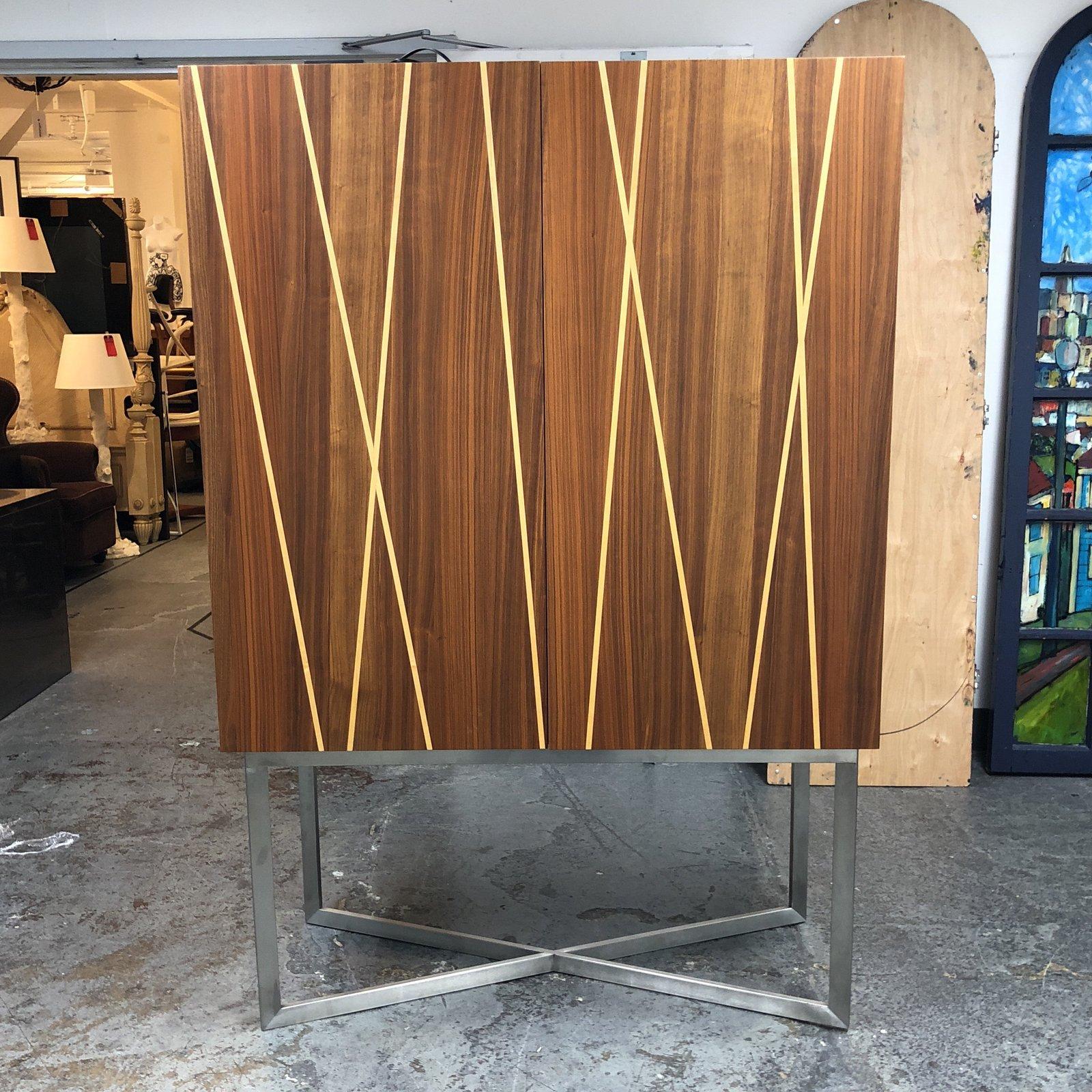 A solid wood designer bar. Purchased form a showroom in San Francisco. The front doors has a ribbon inlay. The inside consist of a mirrored back with overhead lighting. Two pullout drawers with a removable and adjustable single shelf. Over overhead