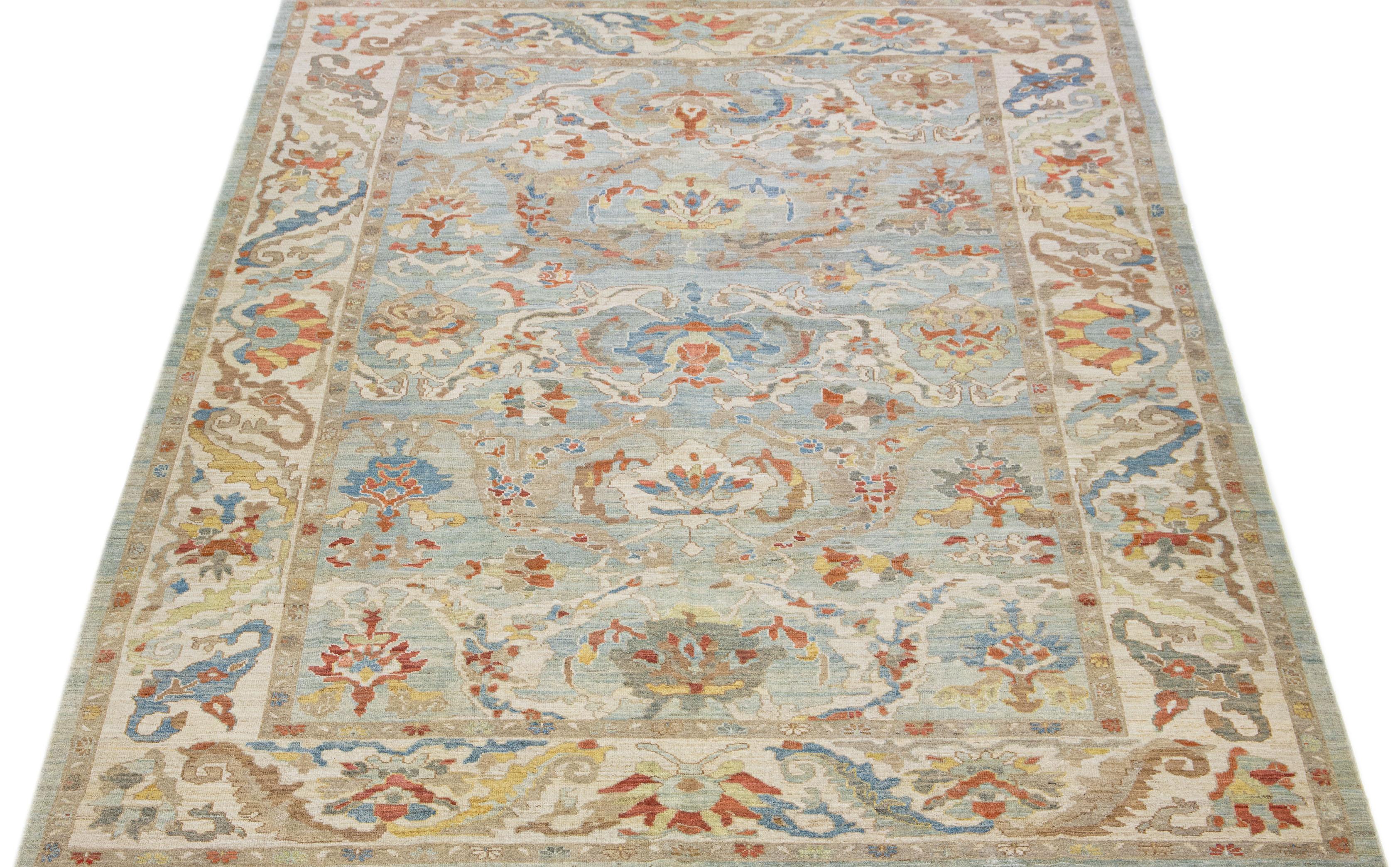 This exquisite hand-knotted wool rug, boasting a captivating blue color field, is a contemporary rendition of the classic Sultanabad style. Its intricately designed beige frame is complemented by an all-over floral motif featuring multicolored