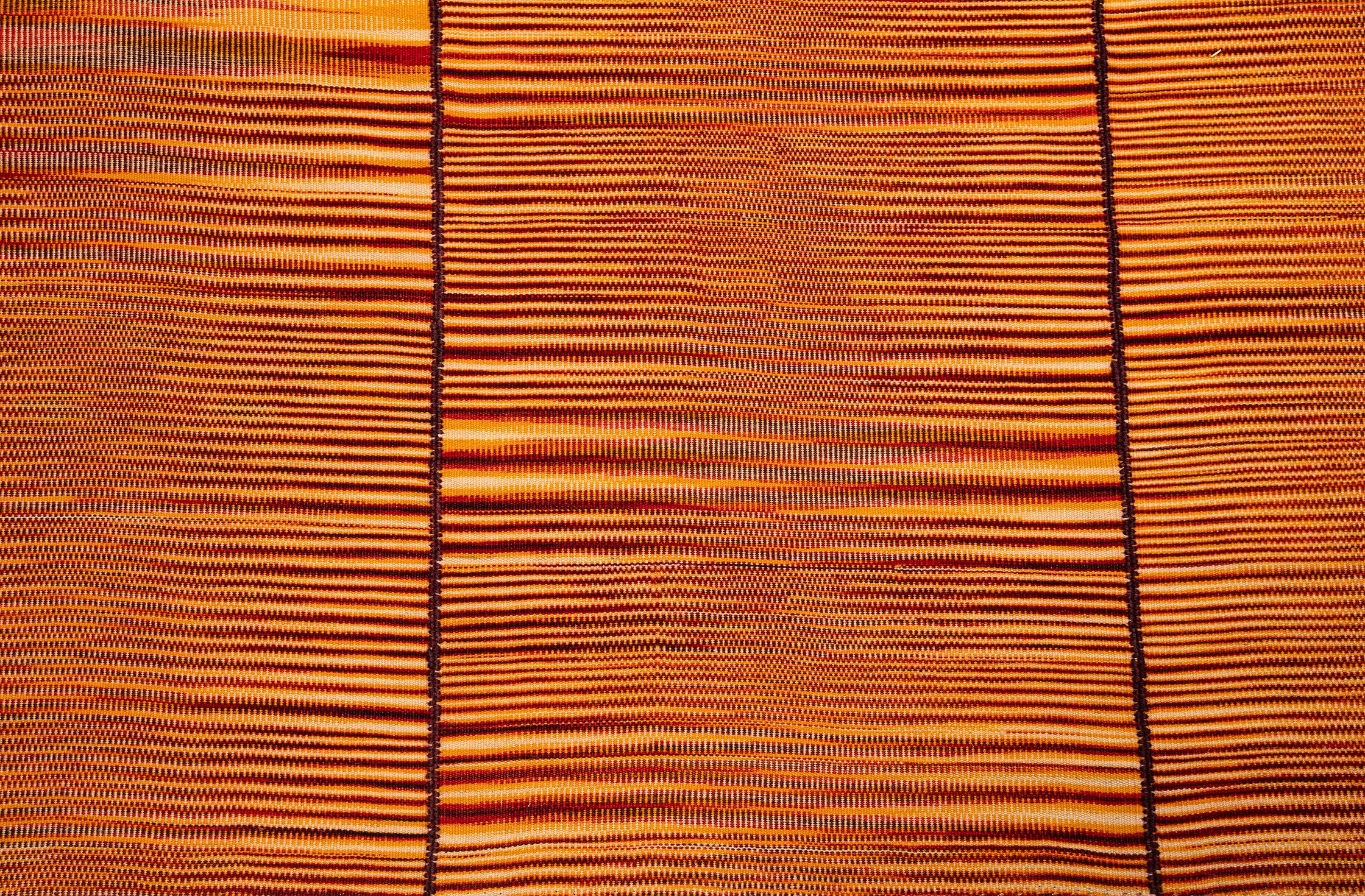 Dieser auffällige Flachgewebeteppich ist aus handgekämmter und handgesponnener Wolle gefertigt.  Die pflanzlichen Farbstoffe und die handgefertigte Natur des Stücks sorgen für schöne Variationen.  Dieser Teppich hat sowohl Mid-Century- als auch