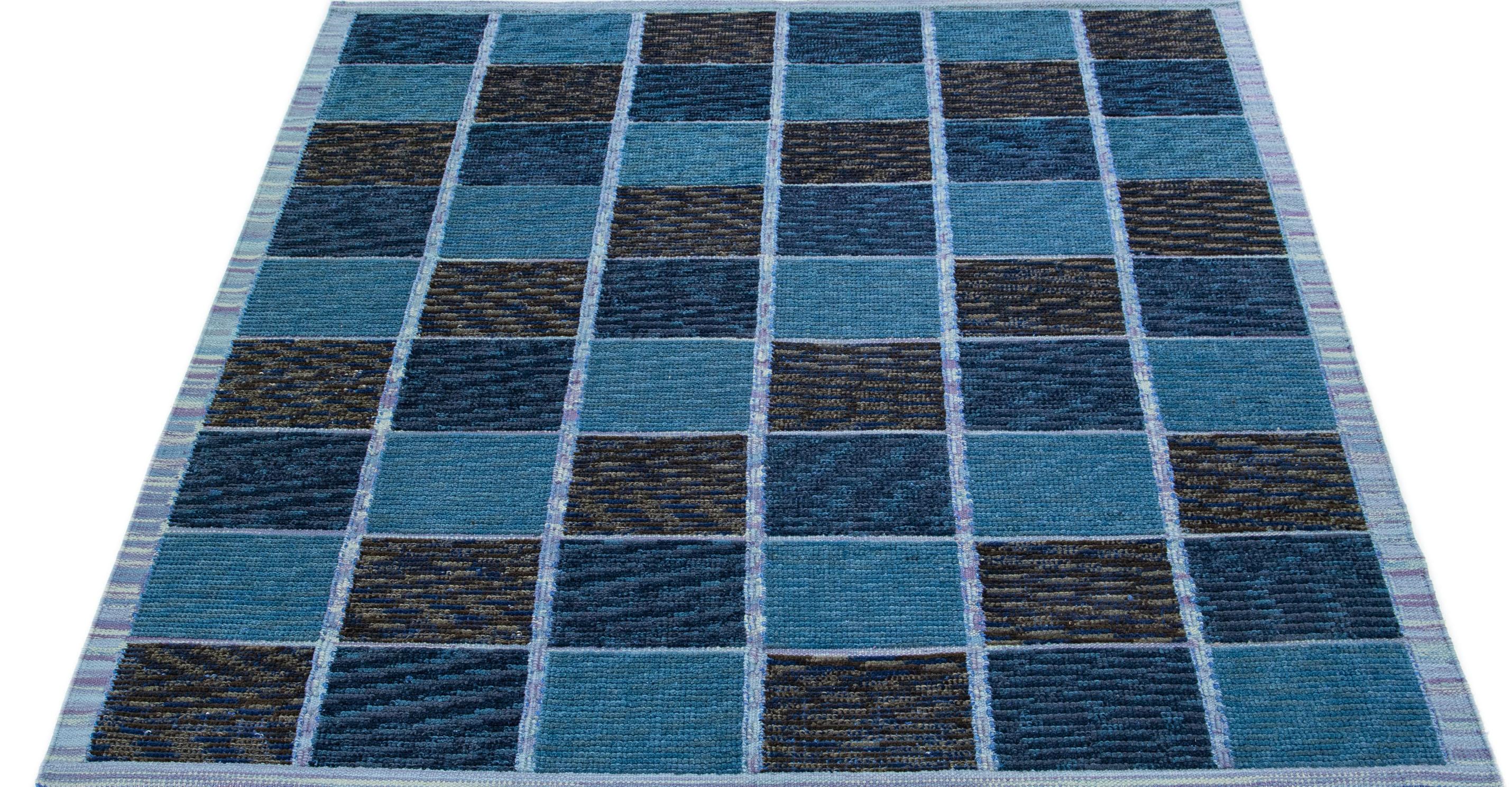 Dieser atemberaubende Wollteppich besticht durch seine zeitgenössische schwedische Ästhetik mit einem fesselnden blauen Farbfeld. Das sorgfältig gearbeitete Karomuster umhüllt den Teppich und verleiht ihm ein wunderschönes Gesamtbild.

 Dieser
