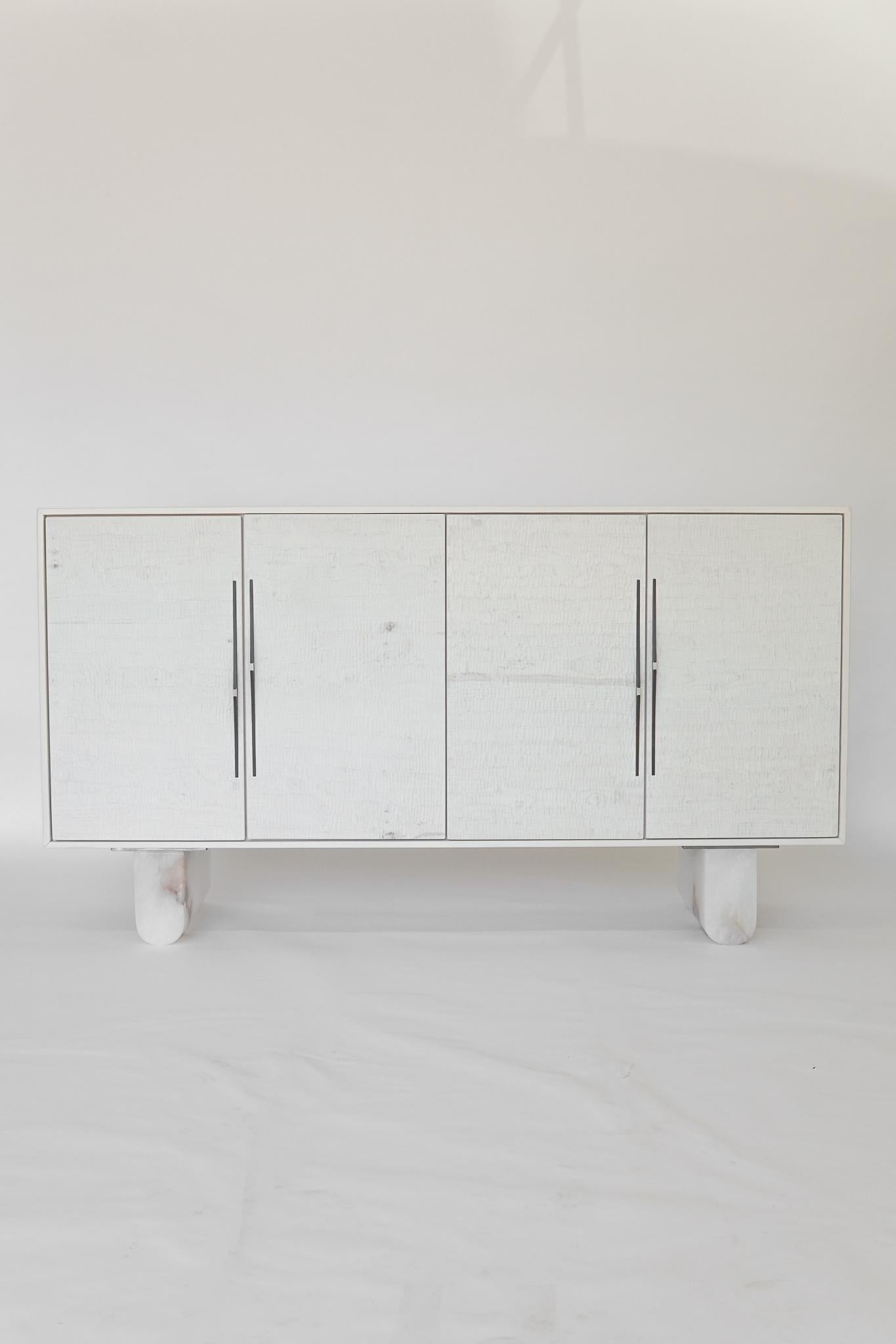 Custom modern bleached maple storage unit in bleached maple with hand shaped alabaster feet, carved maple doors, and custom pulls. This piece can have drawers added to the interior at an additional cost. 



 