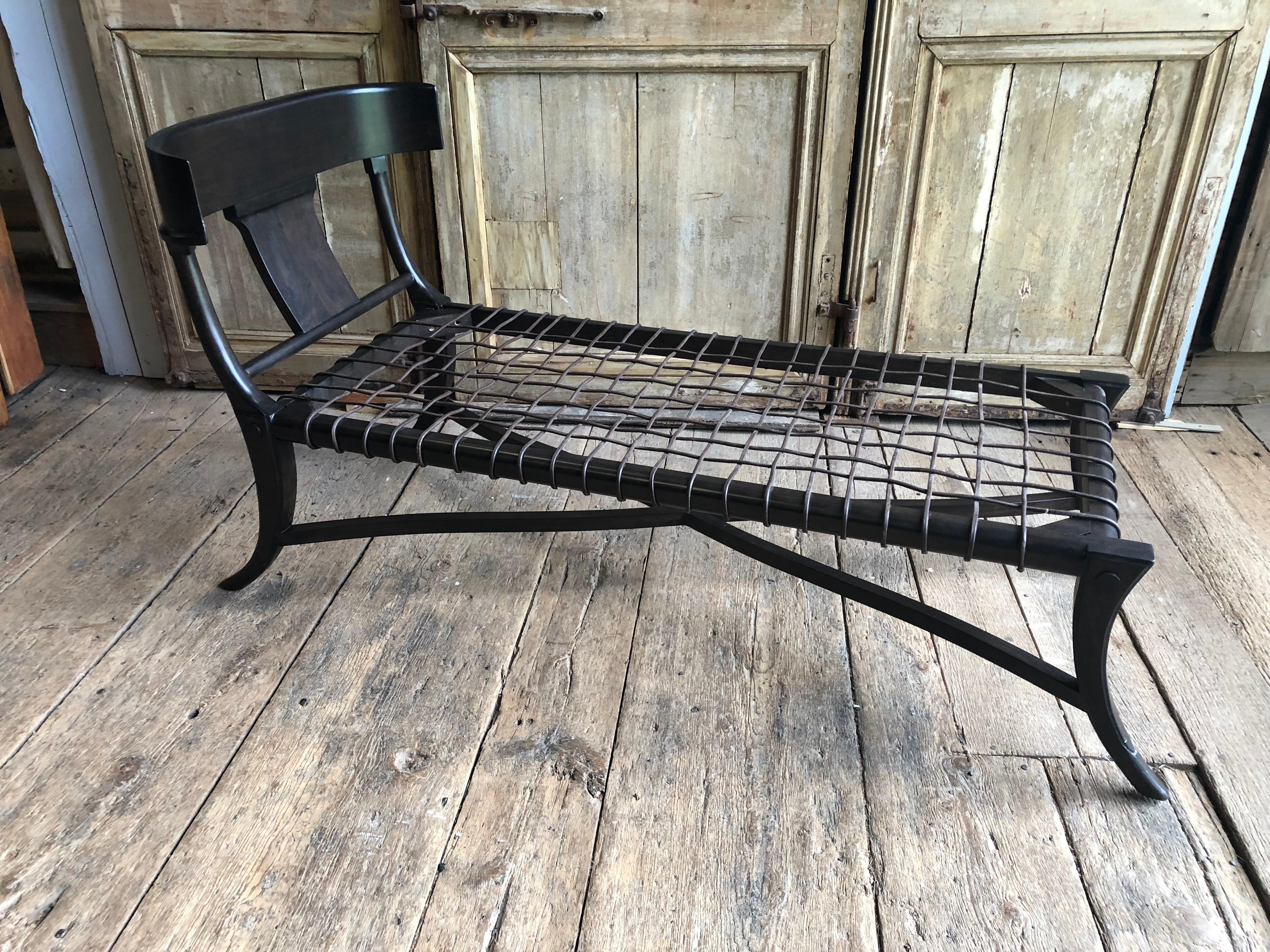 An ebonized “klismos” form lounge chair designed by H. J. Robsjohn Gibbings, contemporary. Lacking cushion. Recommended cushion size 58” x 26”. Contemporary.