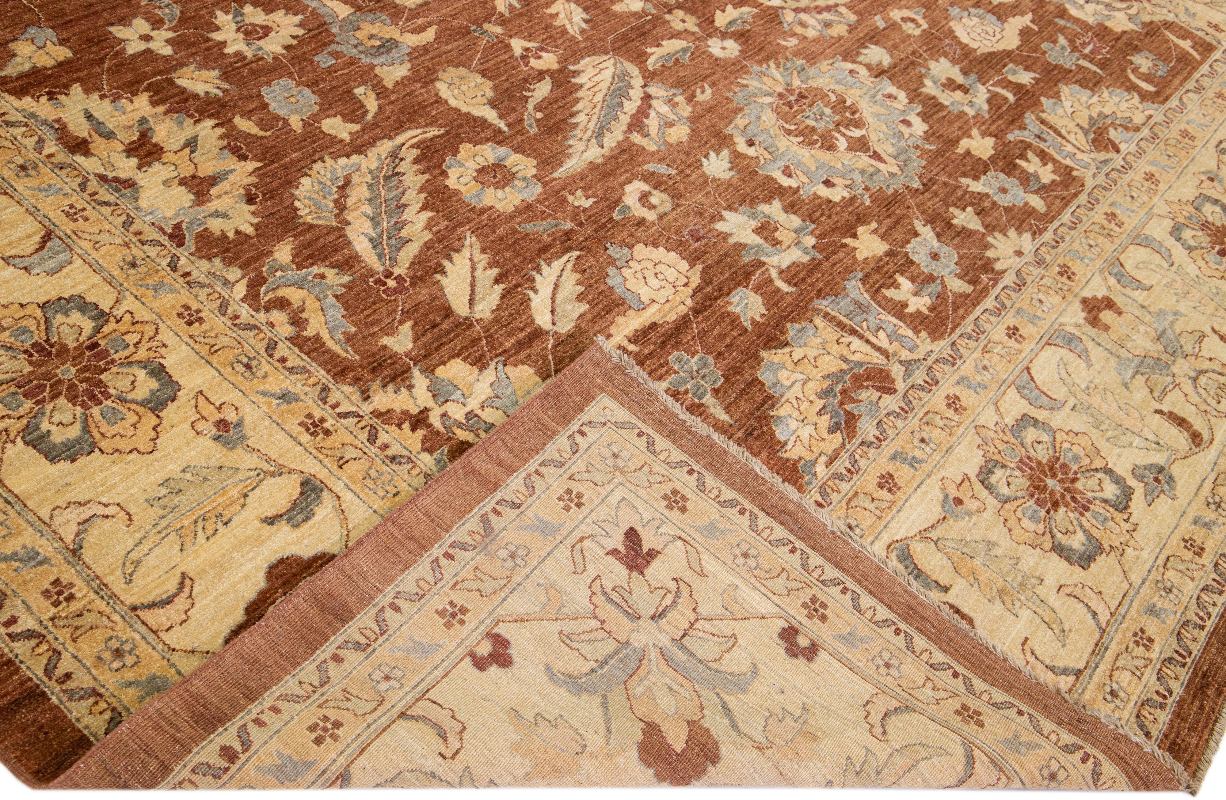 Beautiful antique Tabriz-style hand-knotted wool rug with a brown color field. This piece has a beige and blue accent in a gorgeous floral design.

This rug measures 12'6
