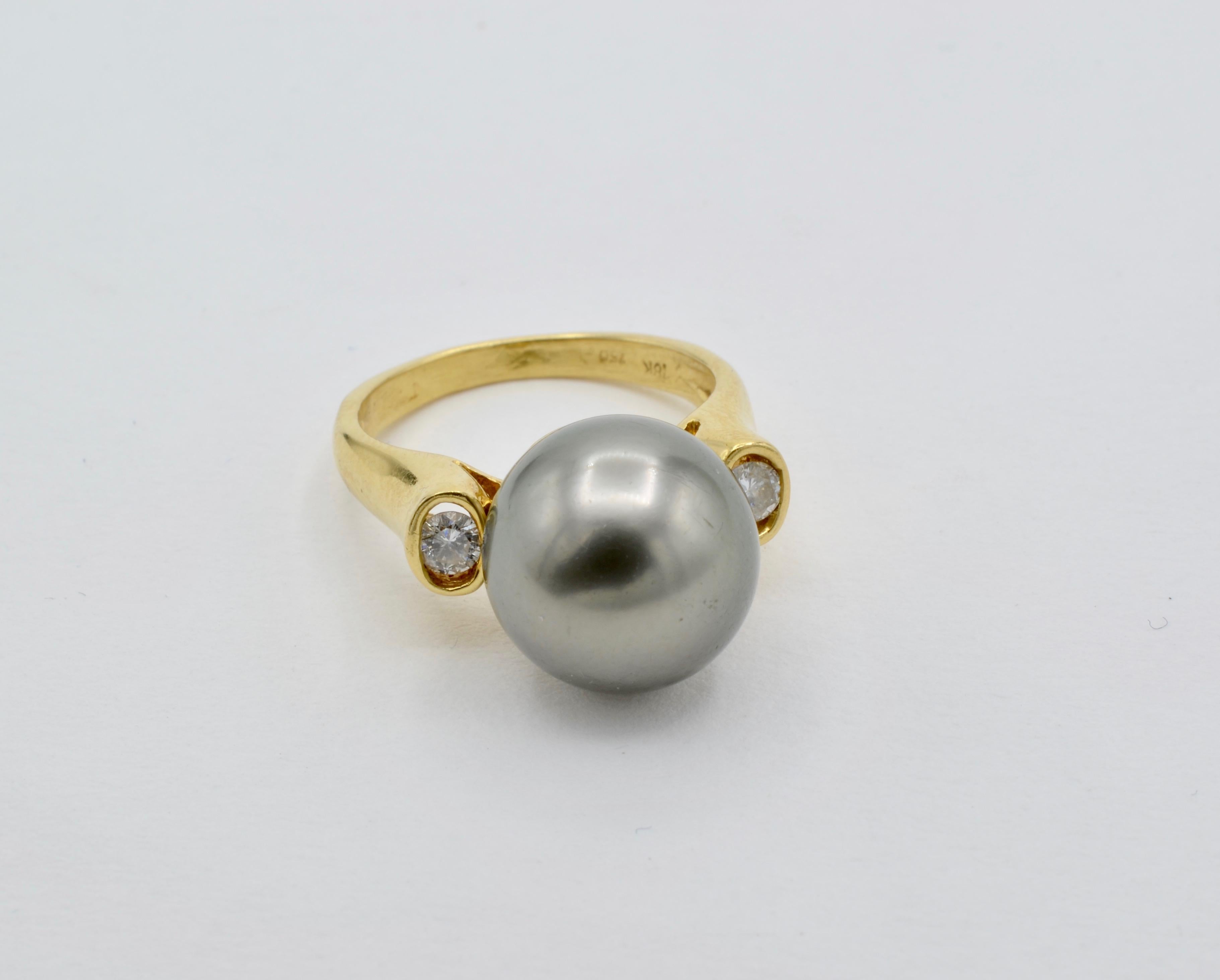 This beautiful Tahitian pearl is beautifully set in 18k gold with two round accent diamonds (aprox 0.20 tw ). The pearl sets high on the bezel to show off the beauty and size (13mm) of the pearl. The ring is a size 7 3/4 and can be sized to fit.



