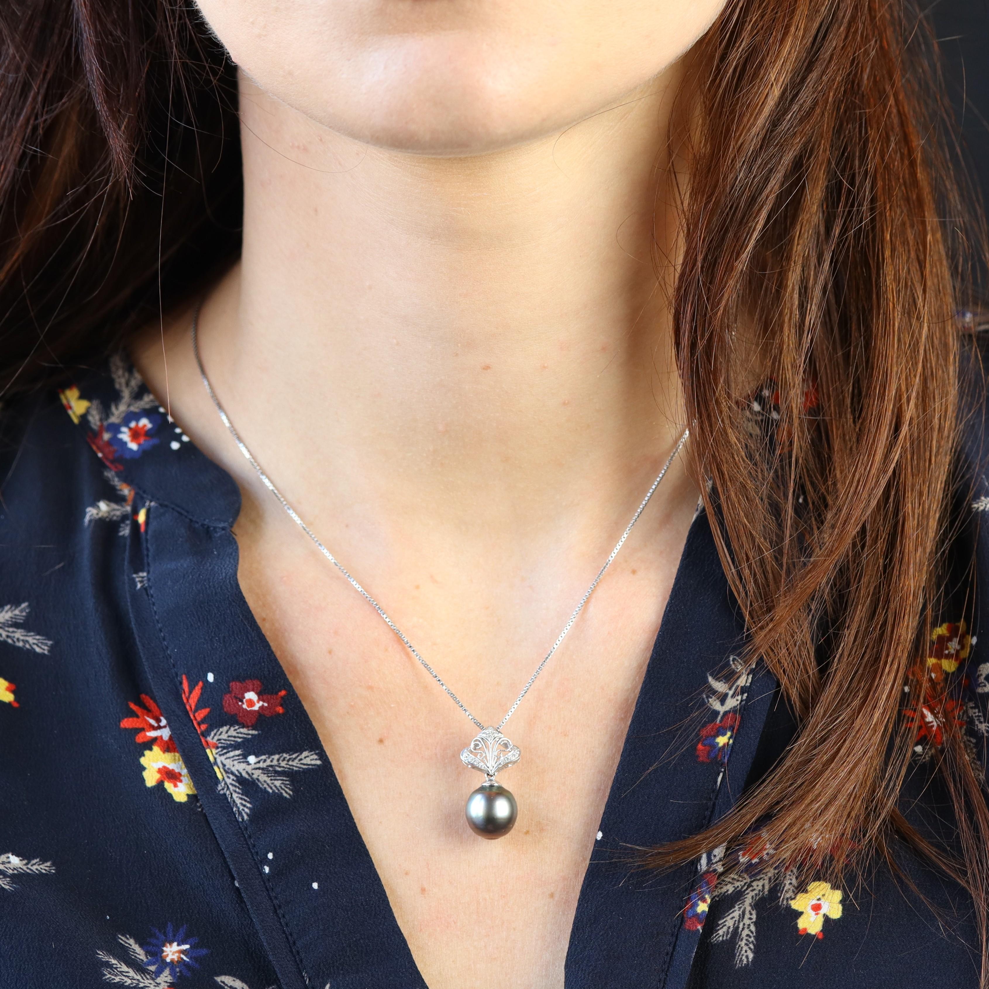 Colgante de oro blanco de 18 quilates.
Este elegante colgante de oro blanco presenta un motivo calado, cincelado y engastado con pequeños diamantes talla brillante modernos. Contiene una gran perla de Tahití de tonos verdes y berenjena. Viene con