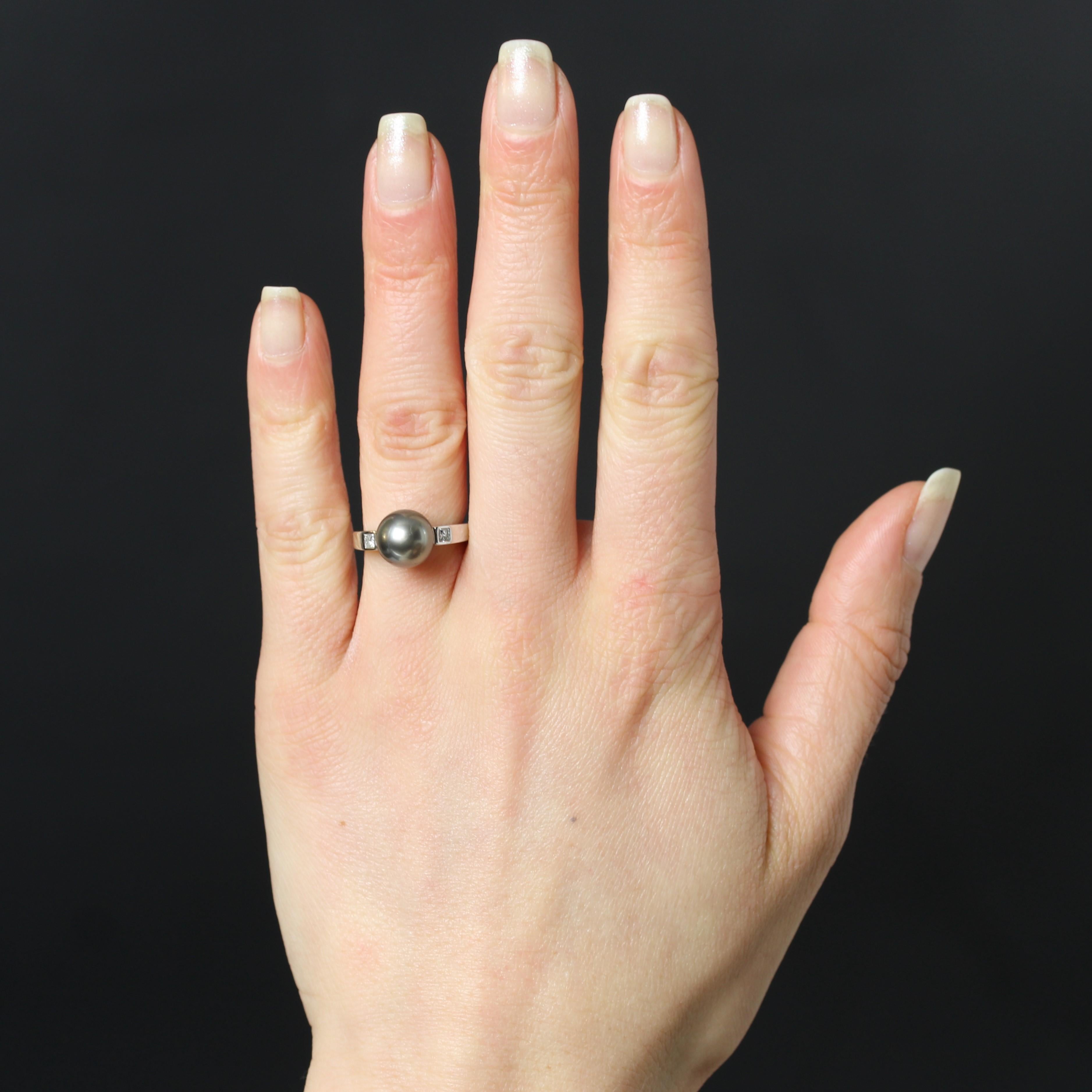 Anello in oro bianco 18 carati, marchio di fabbrica con testa d'aquila.
Anello di seconda mano in oro bianco con una sezione quadrata e una perla coltivata grigia perlata sul davanti, sostenuta su entrambi i lati da 2 diamanti taglio princess in una
