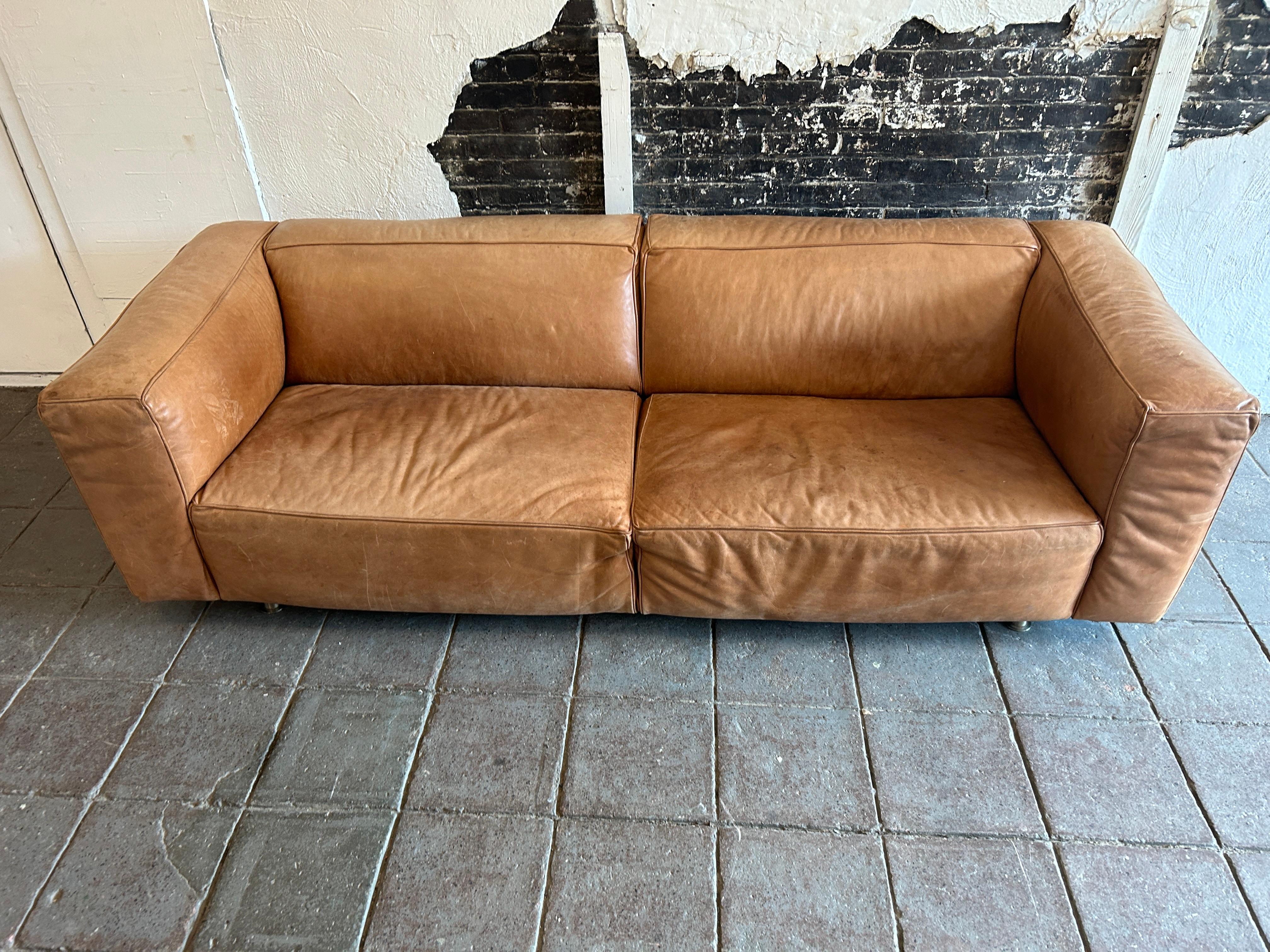 Modern tan Leather Sofa wide cube shaped very high quality leather and very heavy as well built very solid. Tan leather shows patina signs of use with a few small scuffs. Very well broken in and leather shows normal fading from use. You will love