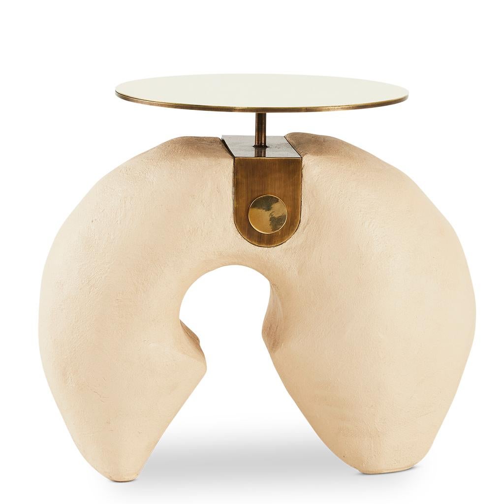 The modern Yoruba side tables are equally beautiful presented individually or as a side table nesting set. 
This small version has a hand finished camel colored Yosemite plaster base. The solid polished brass top is connected to base with a bronzed