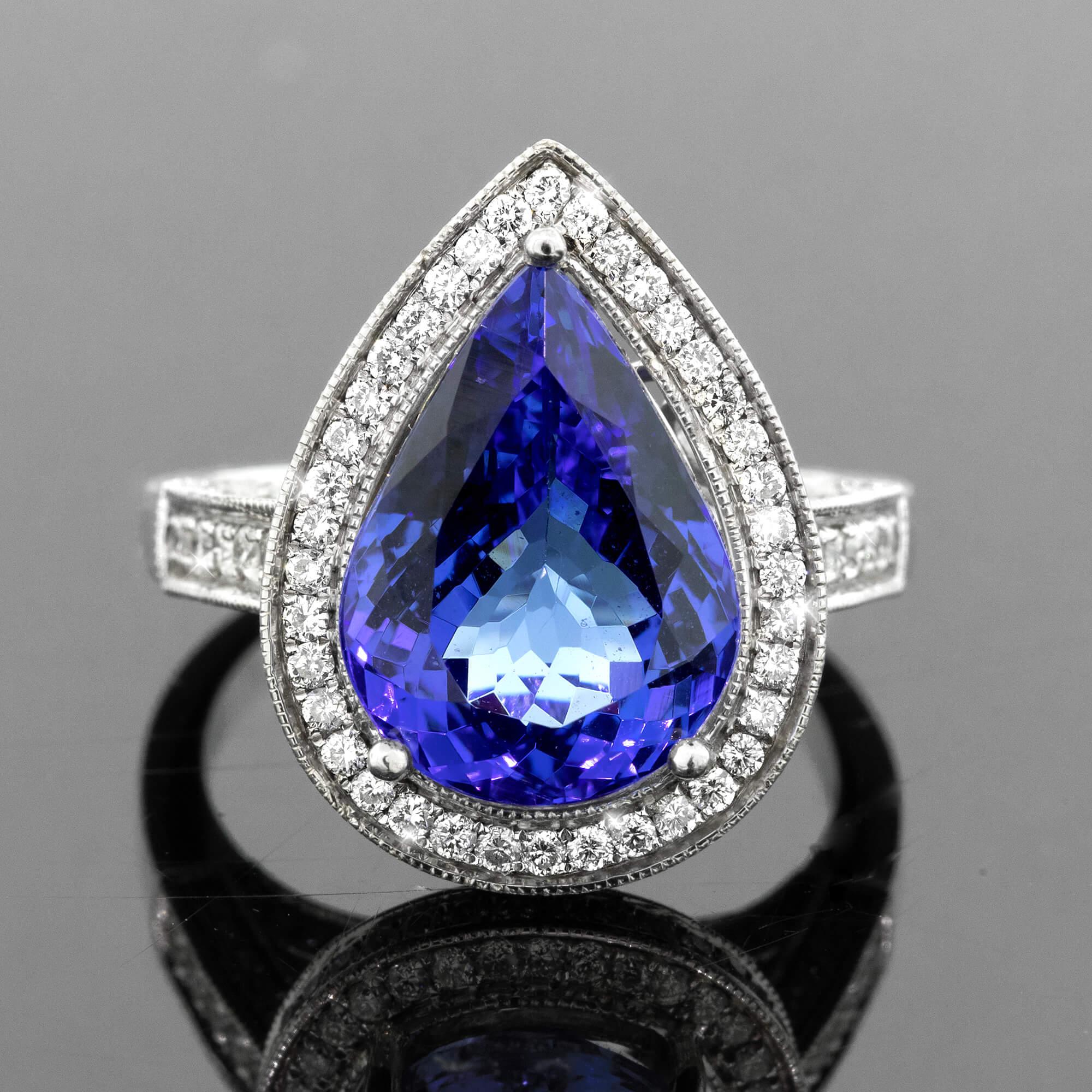 One 14k white gold cast and assembled tanzanite and diamond cluster ring. Featuring a pear cut tanzanite set with three claws. Brilliant cut diamonds grain set in halo, on the side settings and shoulders of the ring. The under gallery has beautiful
