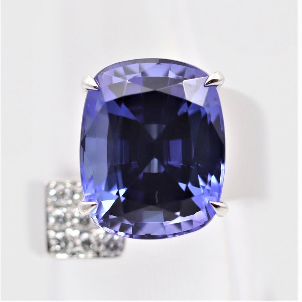 A modern designed ring featuring a 11.69 carat tanzanite with an amazing vibrant gemmy blue-purple color. It has great brilliance and life allowing it to shine brightly. It is accented by 0.34 carats of diamonds set below the tanzanite on the rings