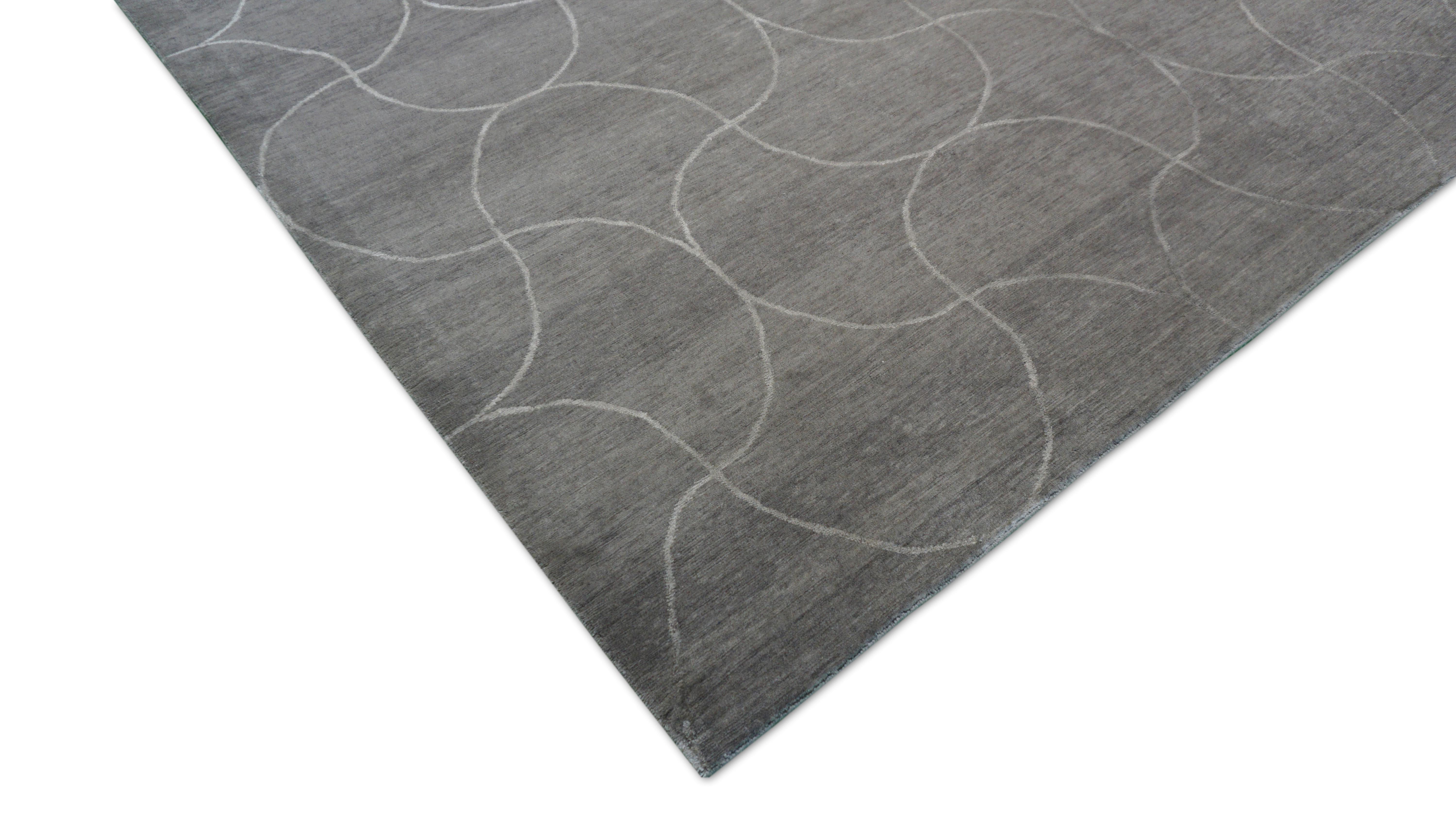 This sophisticated hand-knotted rug showcases a modern geometric motif of ivory overlapping circles subtly embedded in a smooth taupe and gray field. The delicate curvature of the design adds an architectural softness, giving the rug both structure