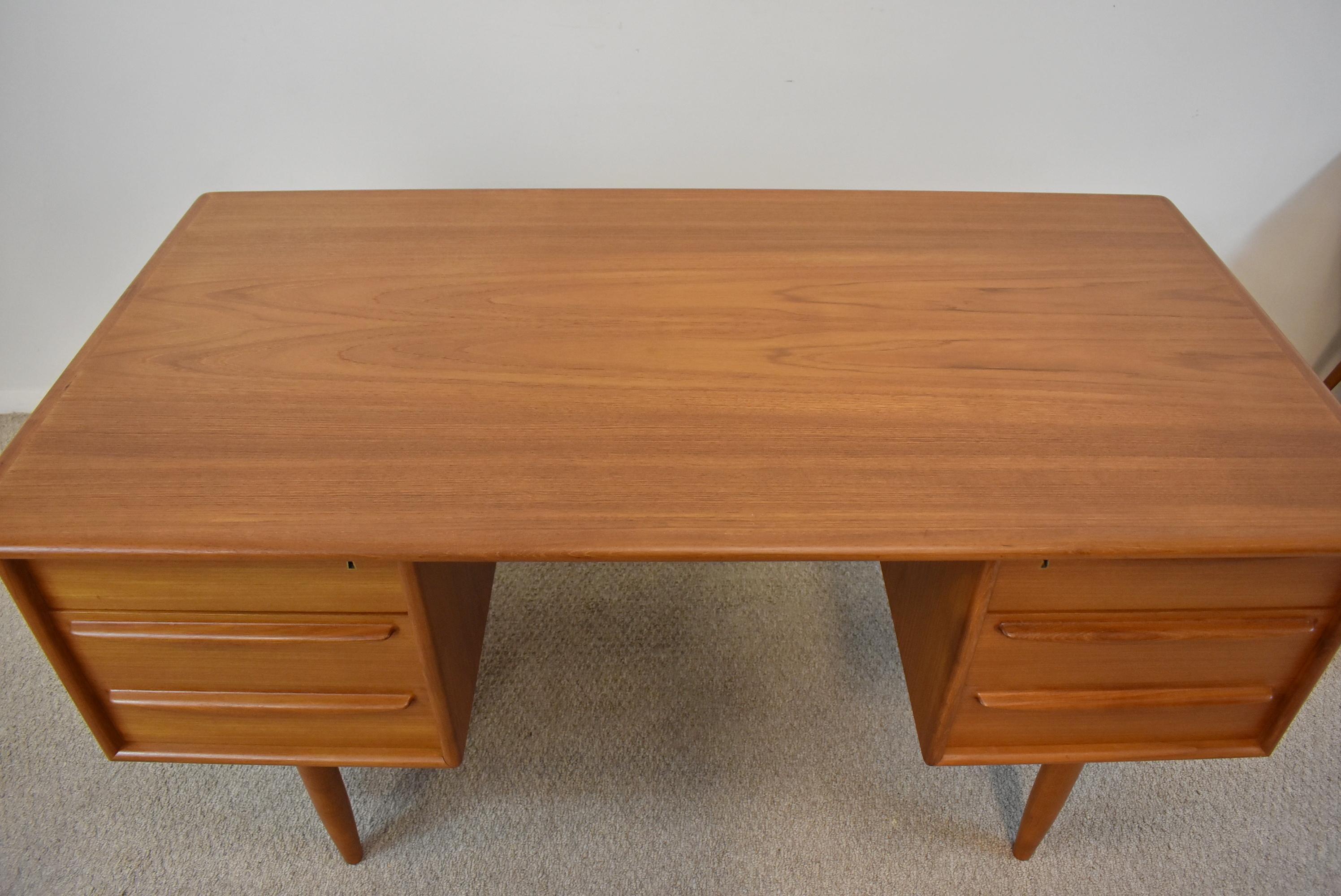 Mid century modern teak desk by Svend Madsen for Falster. Desk has six drawers with tow locking drawers with key. Contoured drawer pulls and dove tail drawer construction. No stains or dents. Excellent condition. 57