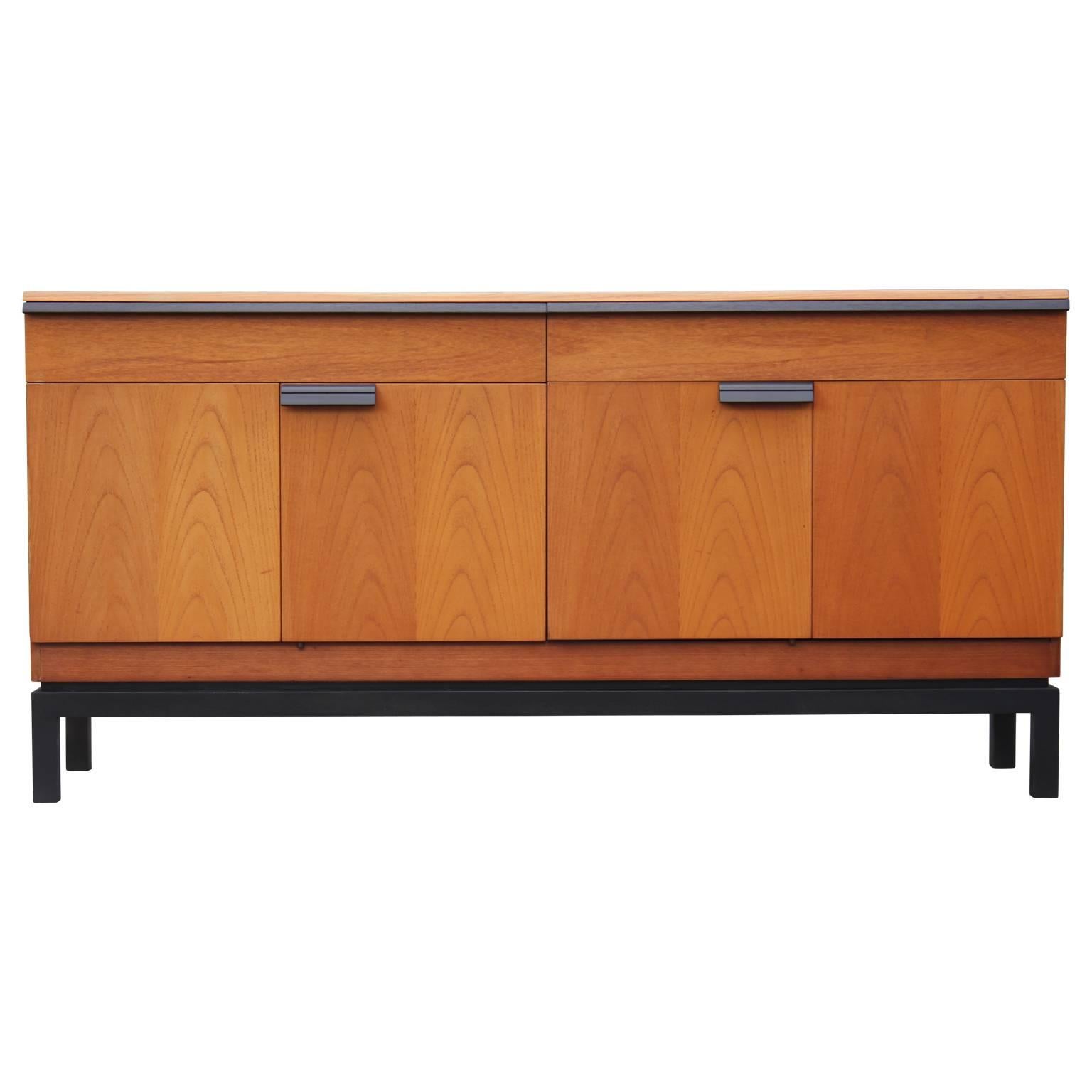 Lovely modern teak two-toned sideboard made in the 1960s. Piece is equipped with two top drawers as well as two larger cabinets with shelves on the bottom. The sideboard has ebony stained handles as well as an ebony stained base.