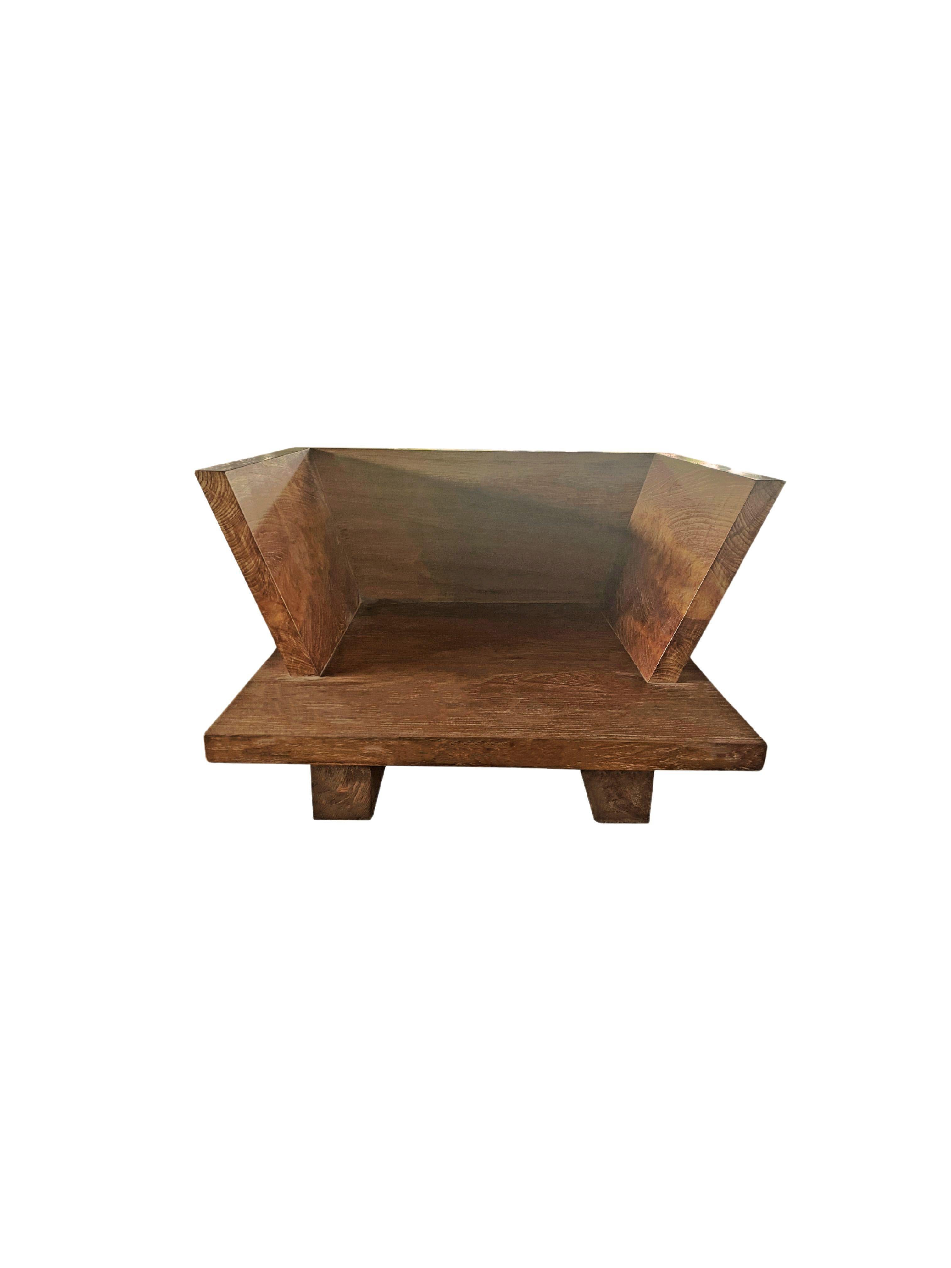 This modern teak wood chair features a large teak wood slab base, backrest and is elevated by two shallow teak wood blocks. This chair is crafted by skilled artisans in Indonesia. This sofa's clear cut shape and minimalist design makes it a suitable