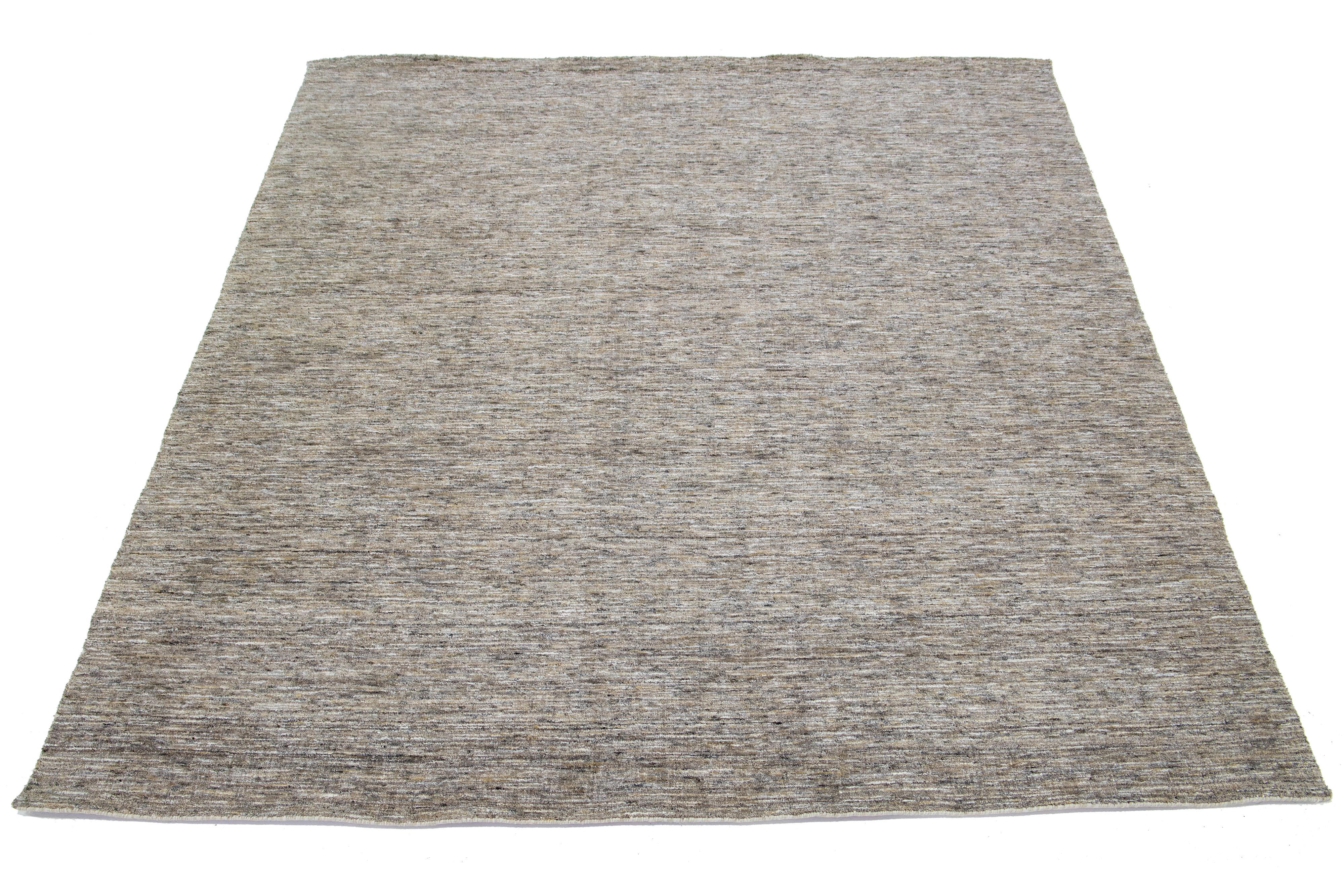 Ce magnifique tapis moderne en laine nouée à la main présente un champ de couleur taupe et un magnifique motif de texture Strié. Cette pièce est parfaite pour faire une déclaration, et sa texture luxueuse laissera une impression durable.

Ce tapis