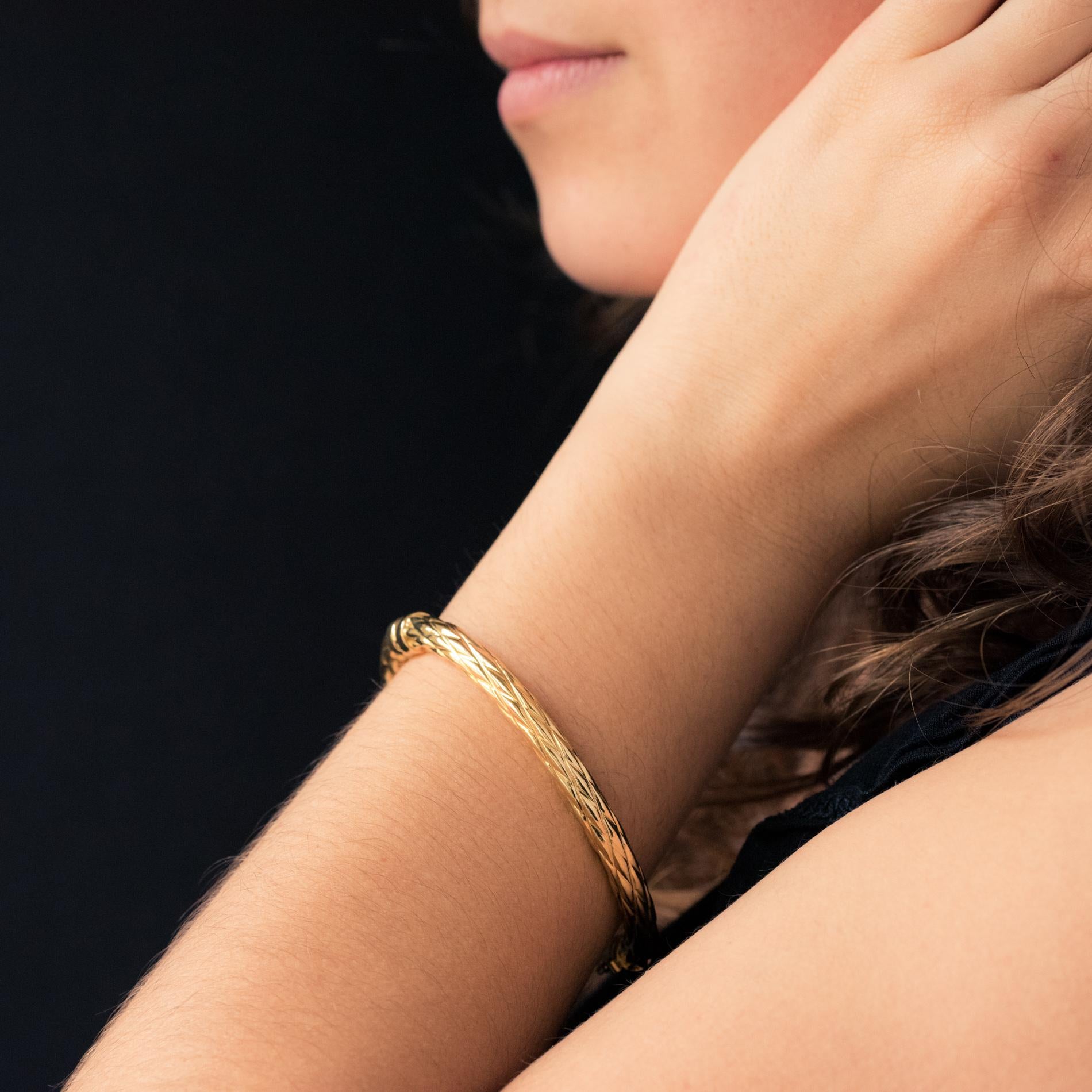 Bracelet in 18 karat yellow gold.
Textured oval bangle bracelet. It opens with a spring hinge on one side. The grip is with a safety 