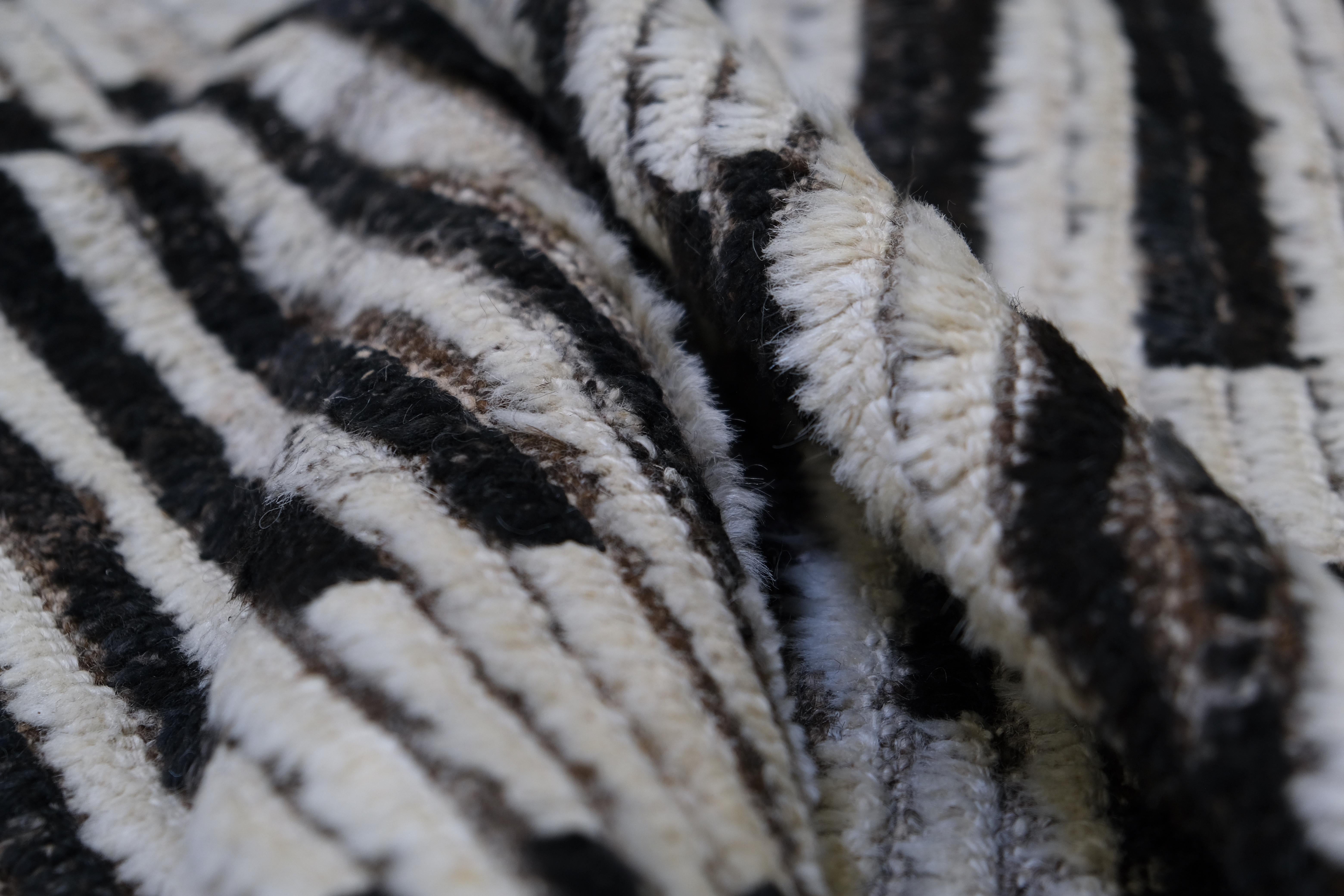 Esta alfombra de lana anudada a mano presenta un llamativo diseño monocromático a rayas, que combina los atemporales tonos blanco y negro para lograr una estética atrevida pero versátil. Los intrincados detalles del dibujo crean una sensación de