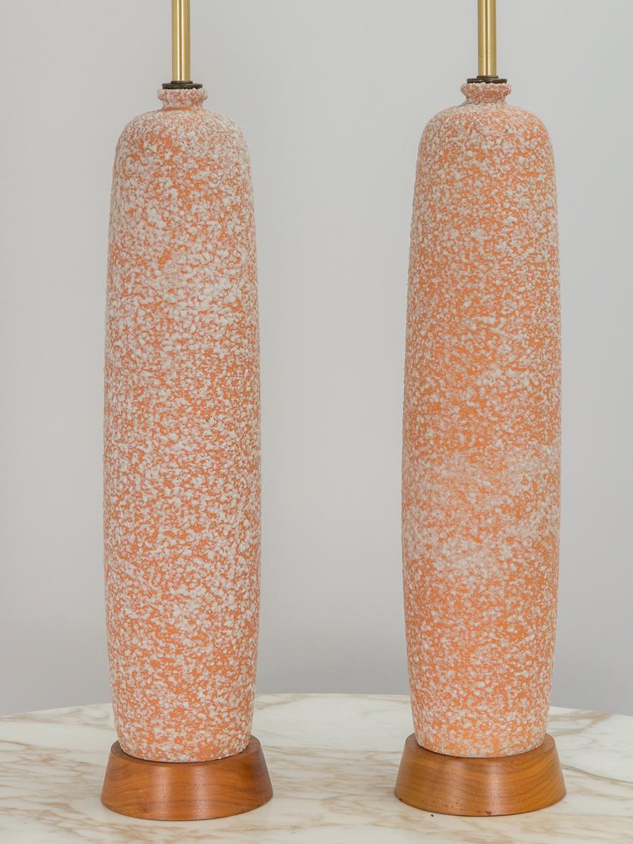 Stylish pair of textured ceramic table lamps on a walnut base. Elongated, organic form with a textured corral and white glaze finish. Likely American in origin, these table lamps stand very tall at 32 inches high. Excellent condition, with no chips