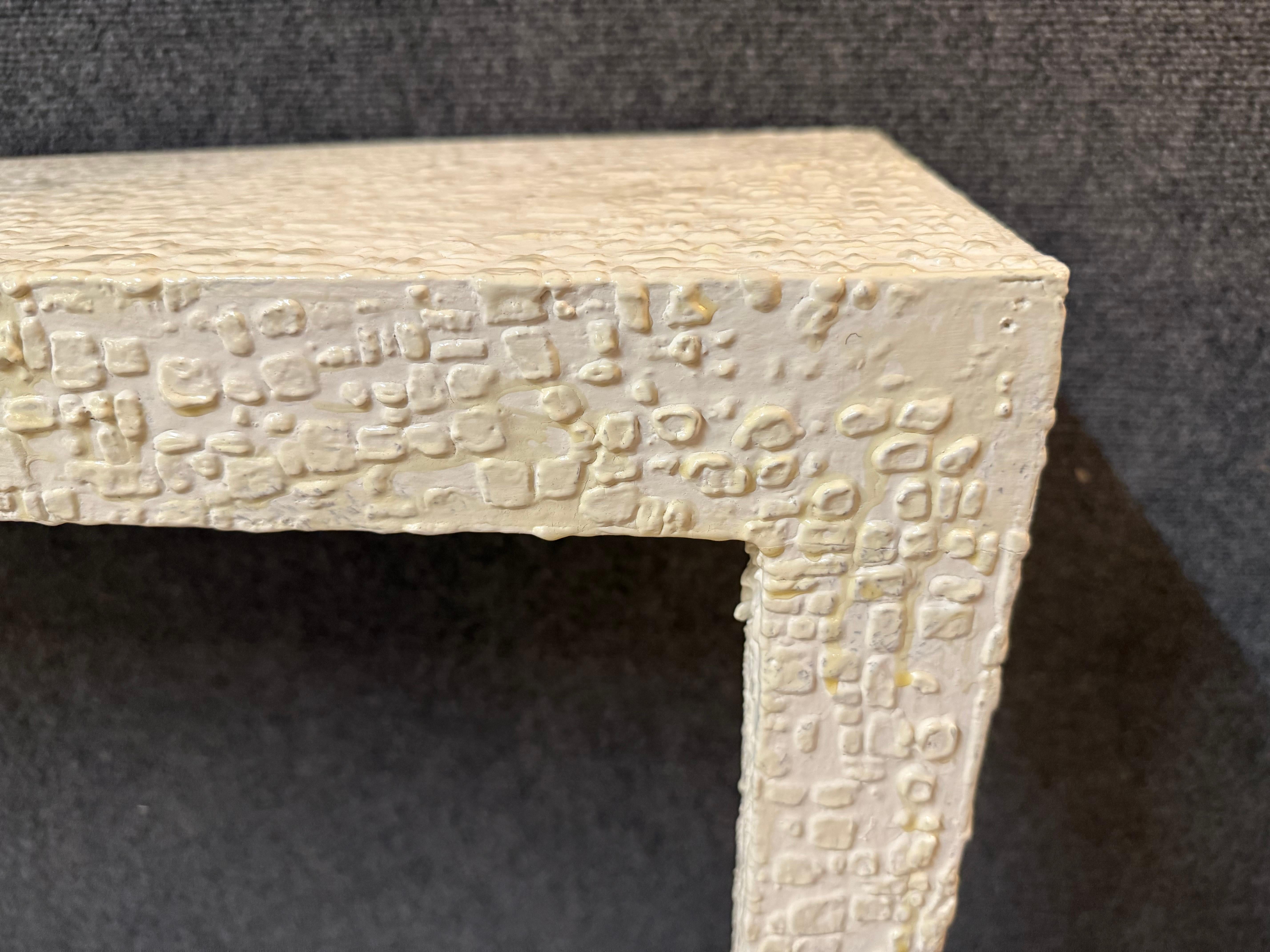 This wall console is an example of sculptural minimalism; this console table combines architectural form with artistic texture. The rectangular silhouette is covered in a meticulously applied white plaster relief, creating a surface that is both