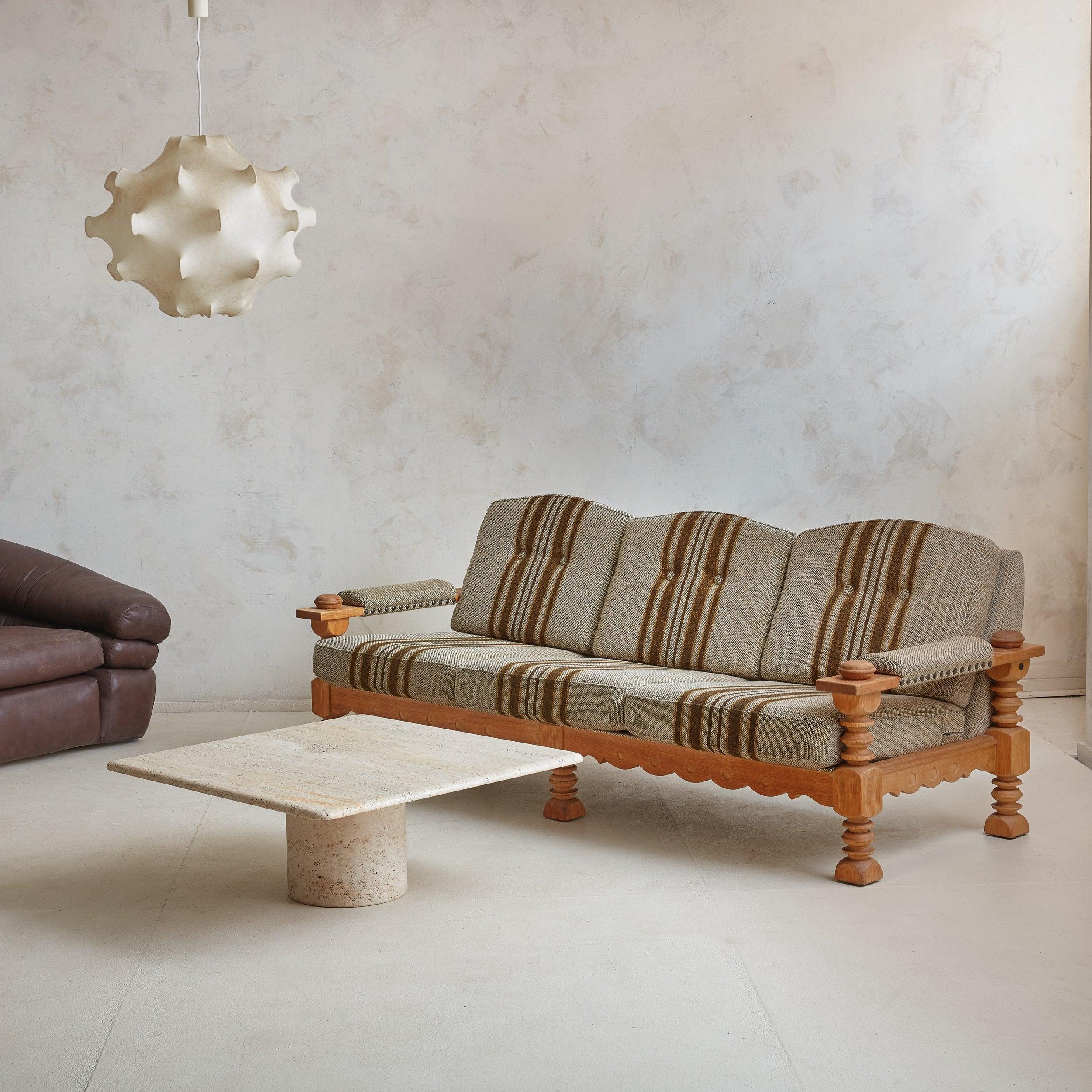 A rare Danish Modern three-seat sofa attributed to Henning Kjærnulf. The Spanish, Mission-inspired silhouette is constructed of warm, white oak and features a scalloped apron, sculpted legs, and thick, half-dome handrests. Striped wool upholstery is