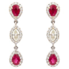 Moderni orecchini a goccia a tre livelli con rubini e diamanti, con montatura a halo in oro bianco 18k