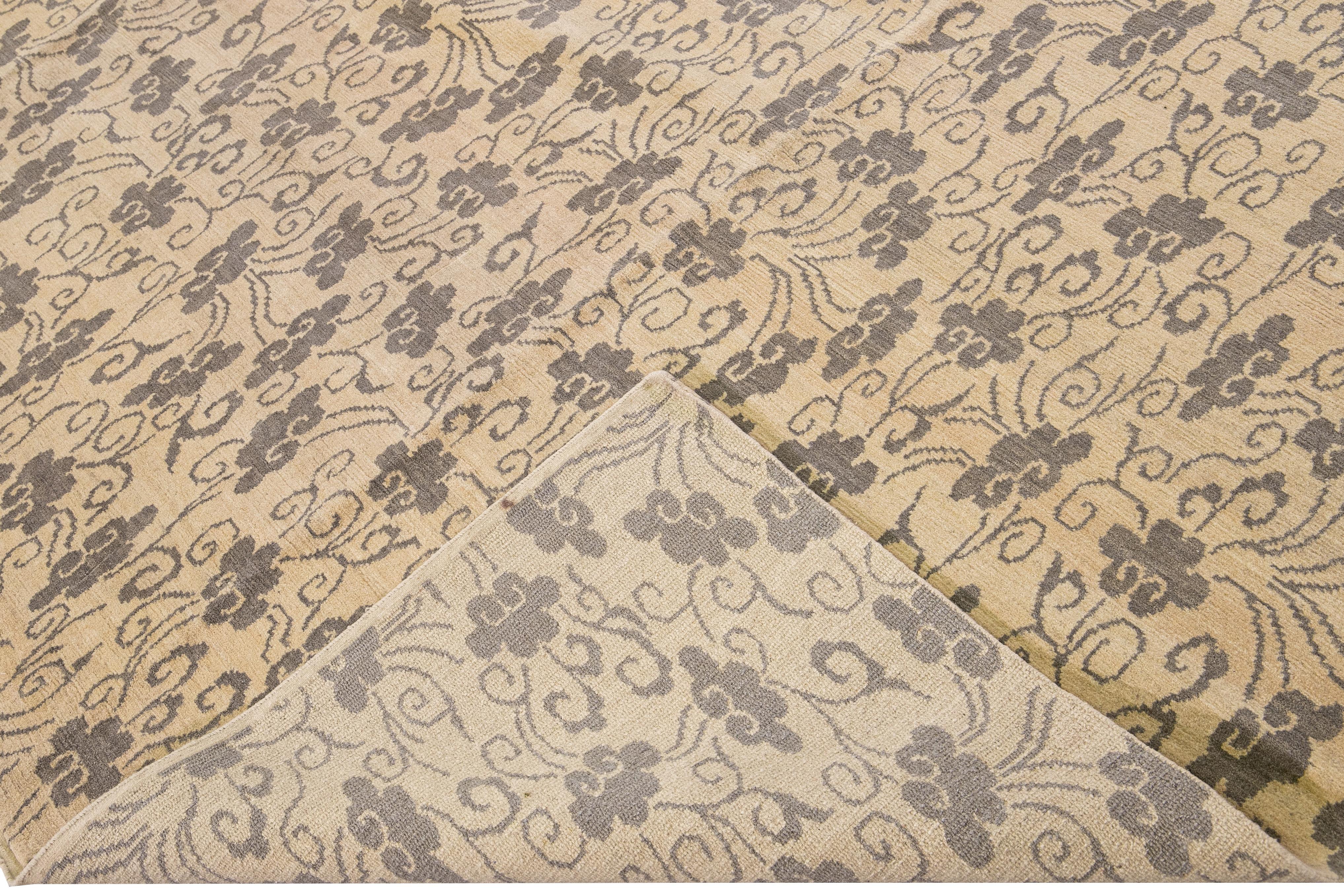 Magnifique tapis tibétain moderne en laine et soie nouée à la main avec un champ beige. Ce tapis tibétain présente des accents gris dans un magnifique motif floral.

Ce tapis mesure 8'3