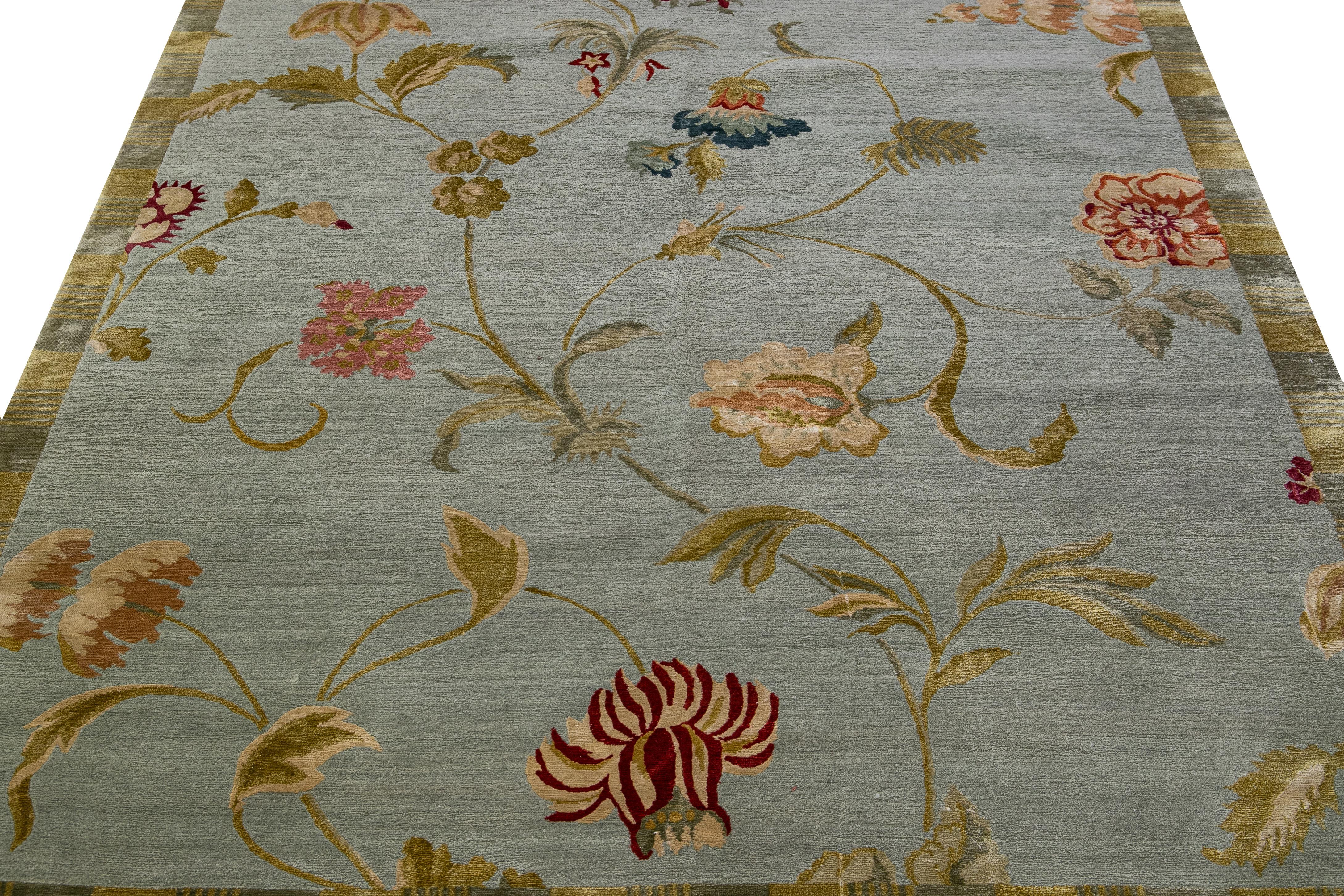 Magnifique tapis tibétain moderne noué à la main en laine et en soie avec un champ gris. Ce tapis tibétain présente des accents rouges, roses, bleus et dorés dans un magnifique motif floral Lyndhurst.

Ce tapis mesure 6'1