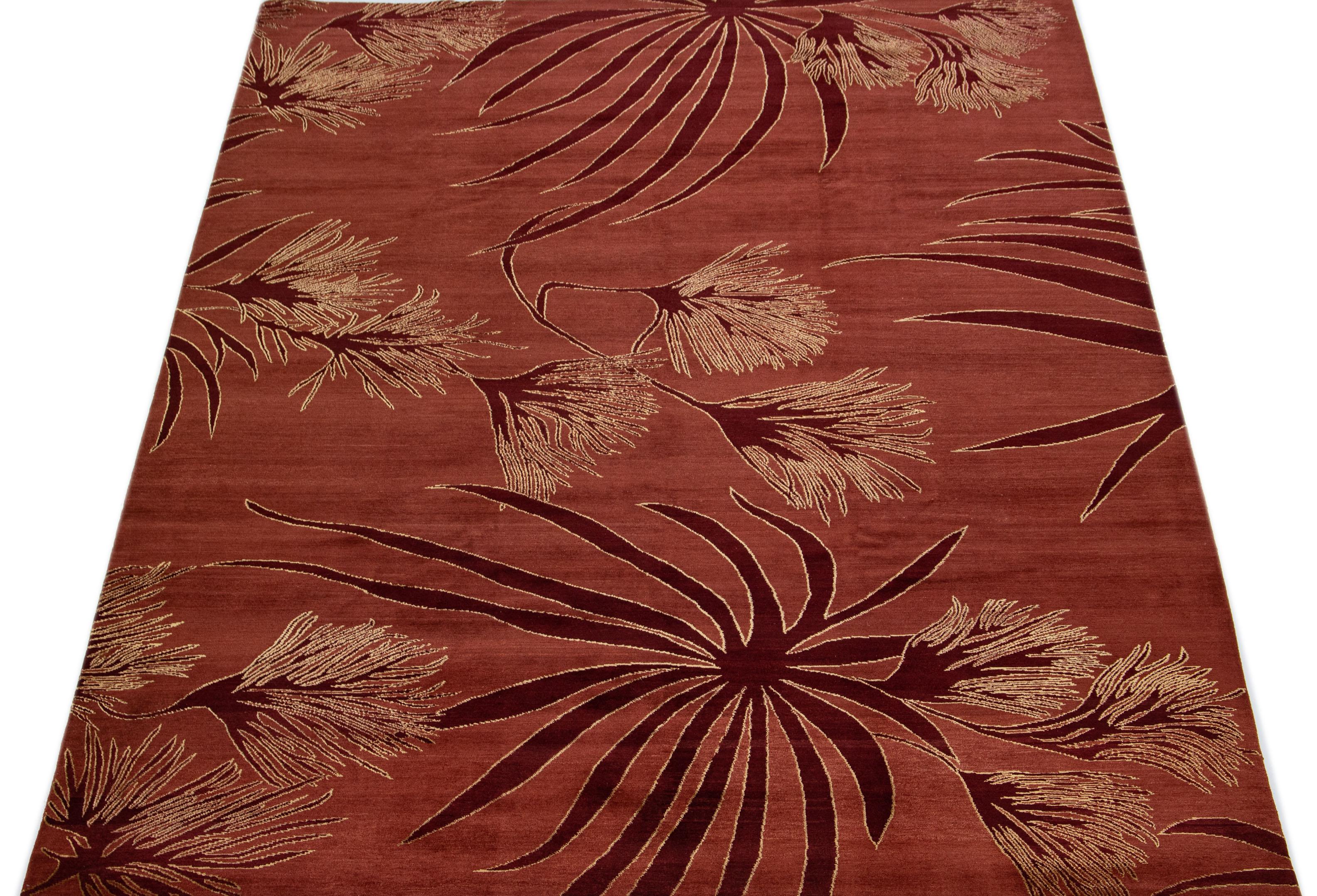Beautiful modern Tibetan hand knotted wool and silk rug with a maroon color field. This Tibetan rug has tan and burgundy accents in a gorgeously floral pattern.

This rug measures 9' x 11'10