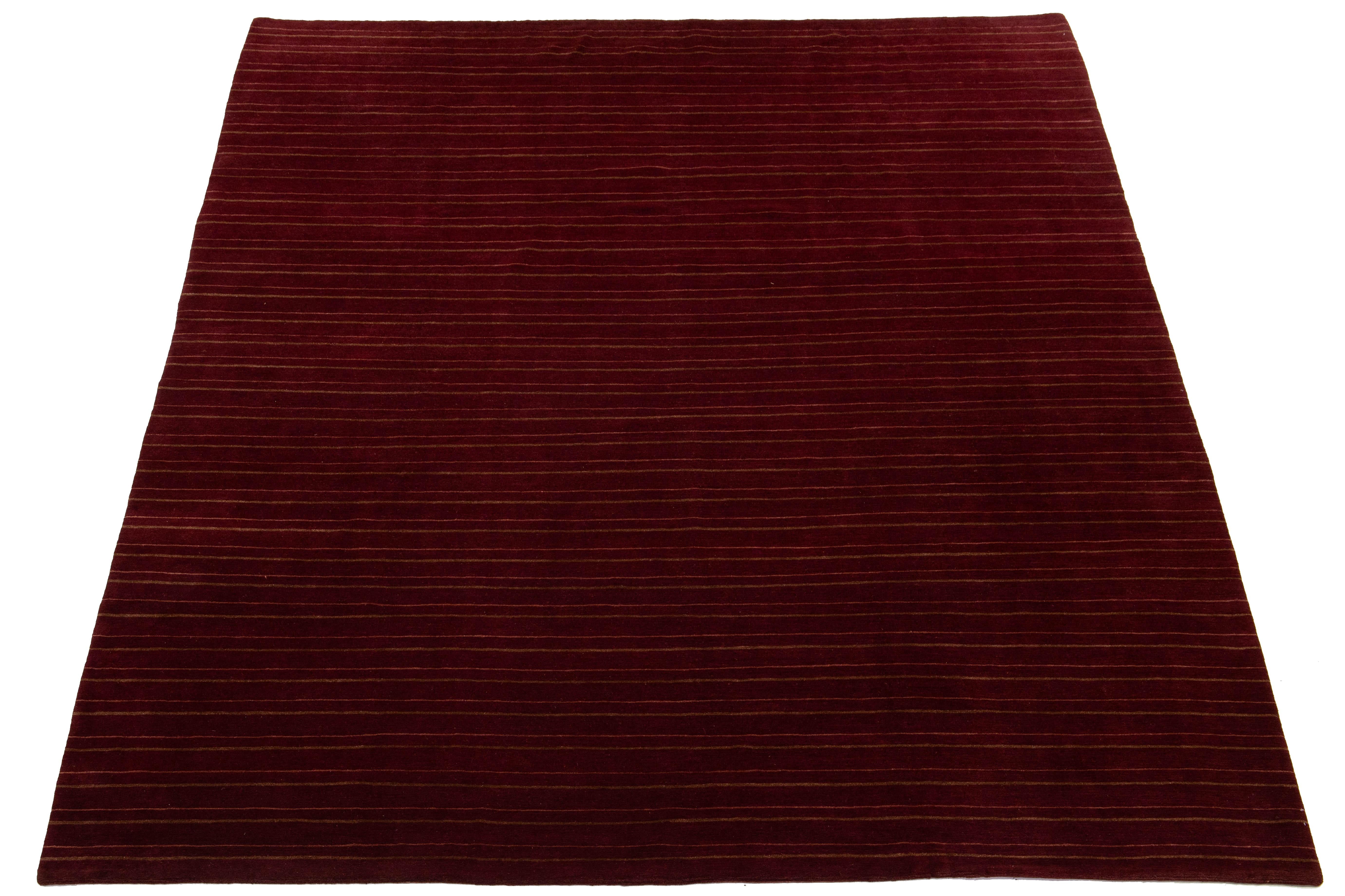 Ce tapis contemporain en tissage tibétain présente un design rayé saisissant dans différentes nuances de brun qui attire immédiatement le regard. Fabriqué en laine ou en soie tibétaine de haute qualité, il arbore des détails complexes et présente un