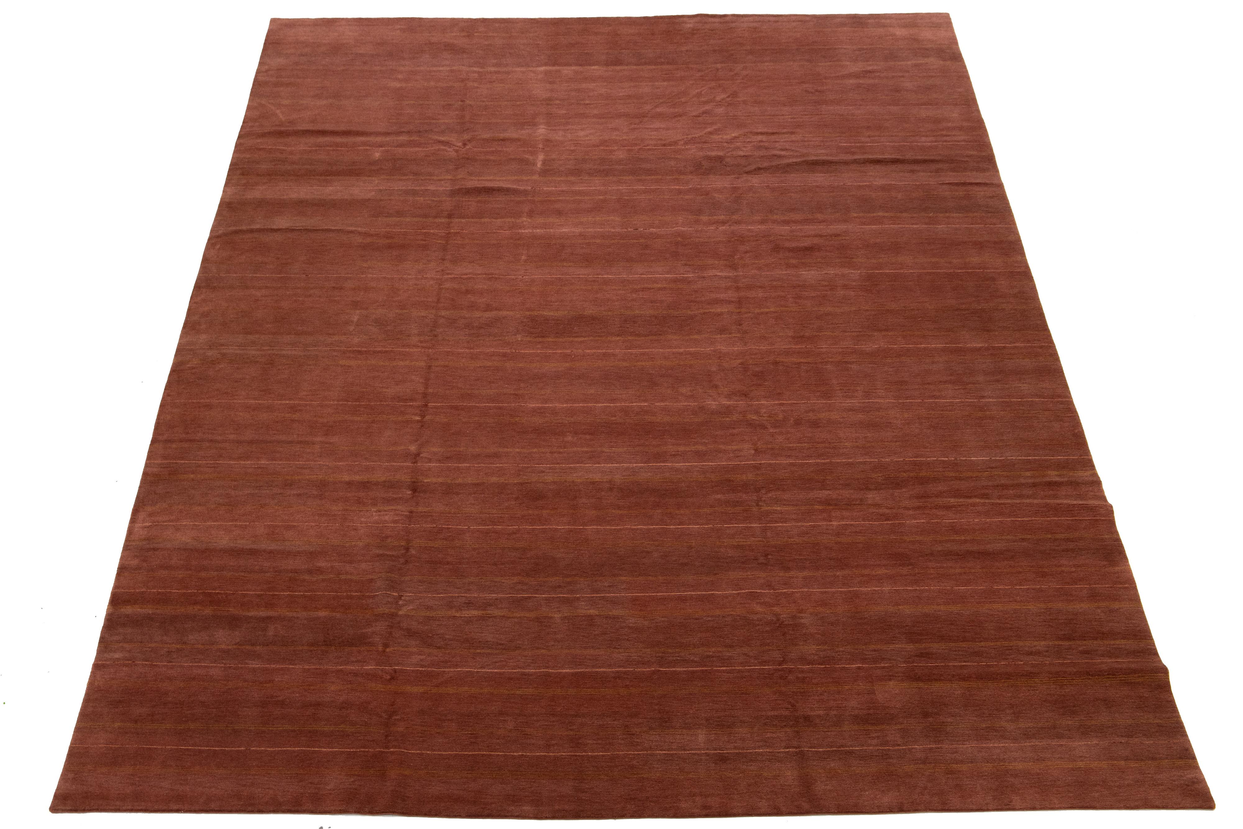 Ce tapis contemporain en tissage tibétain présente un motif frappant de rayures dorées qui attire immédiatement l'attention. Fabriqué en laine ou en soie tibétaine de haute qualité, il présente des détails complexes et possède un champ riche et