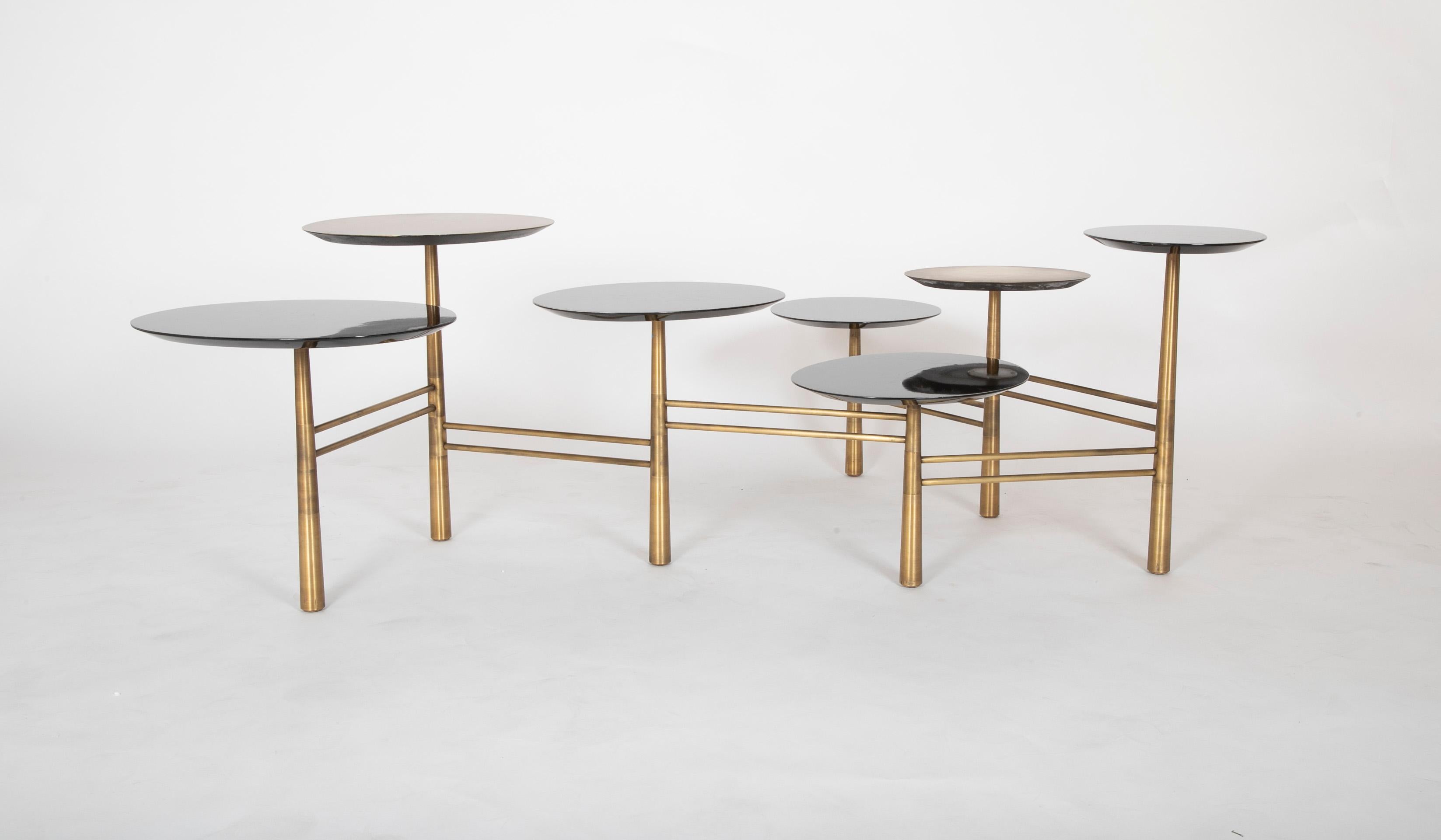 A modern adjustable coffee table with bronze and enameled wood.