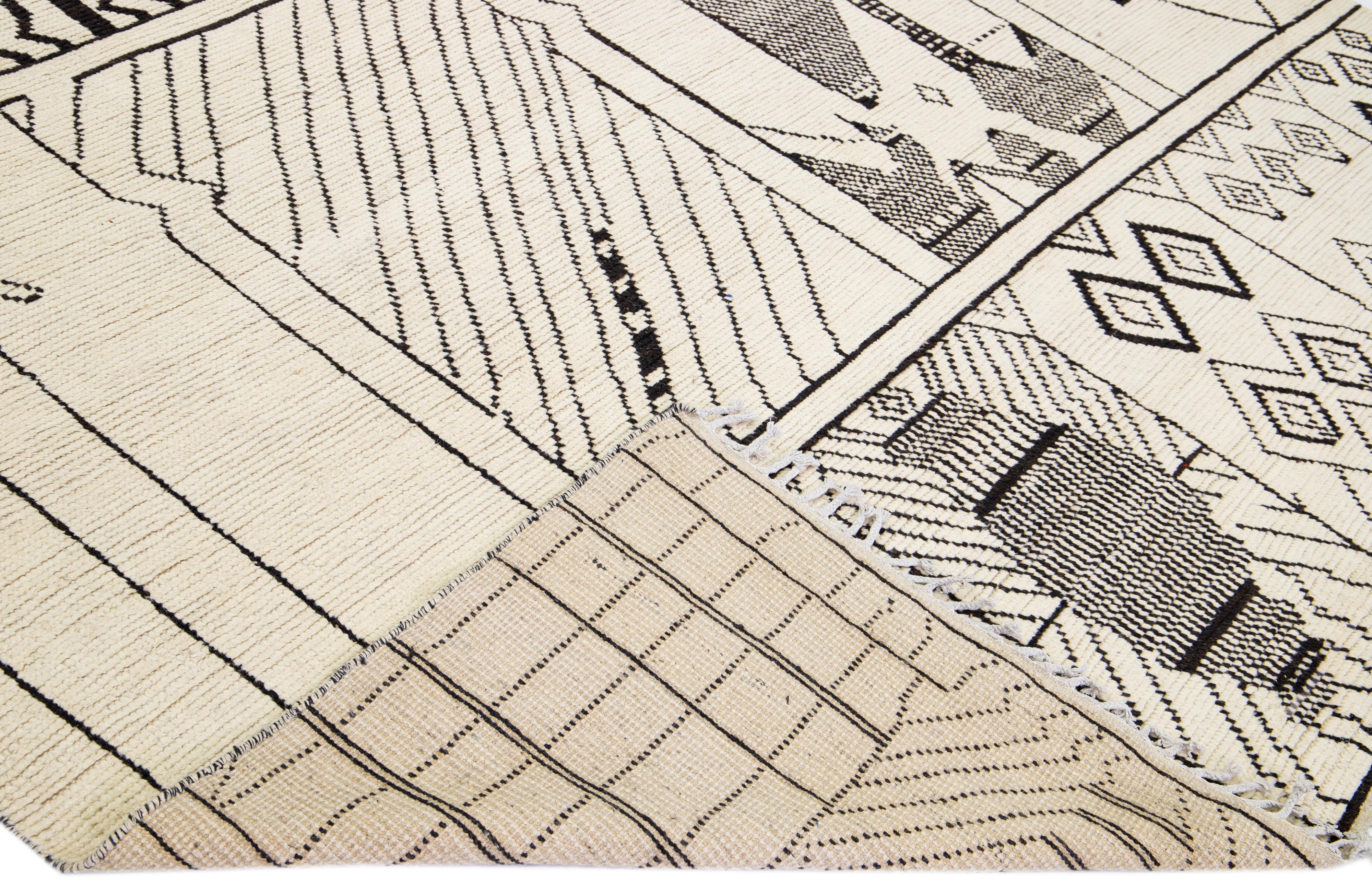 Preciosa alfombra moderna de lana anudada a mano de estilo marroquí con campo beige. Esta pieza tiene un acento de color gris en un precioso diseño tribal con flecos en los extremos superior e inferior.

Esta alfombra mide 9'10