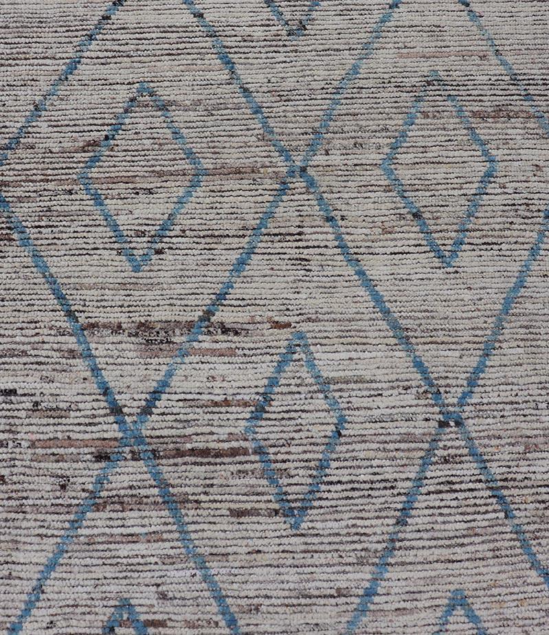 Dieser moderne, lässige Tribal-Galerie-Läufer wurde von Hand geknüpft. Der Teppich zeichnet sich durch ein modernes, subgeometrisches Rautenmuster aus, das in blauen und neutralen Tönen gehalten ist. Damit passt er hervorragend zu einer Vielzahl