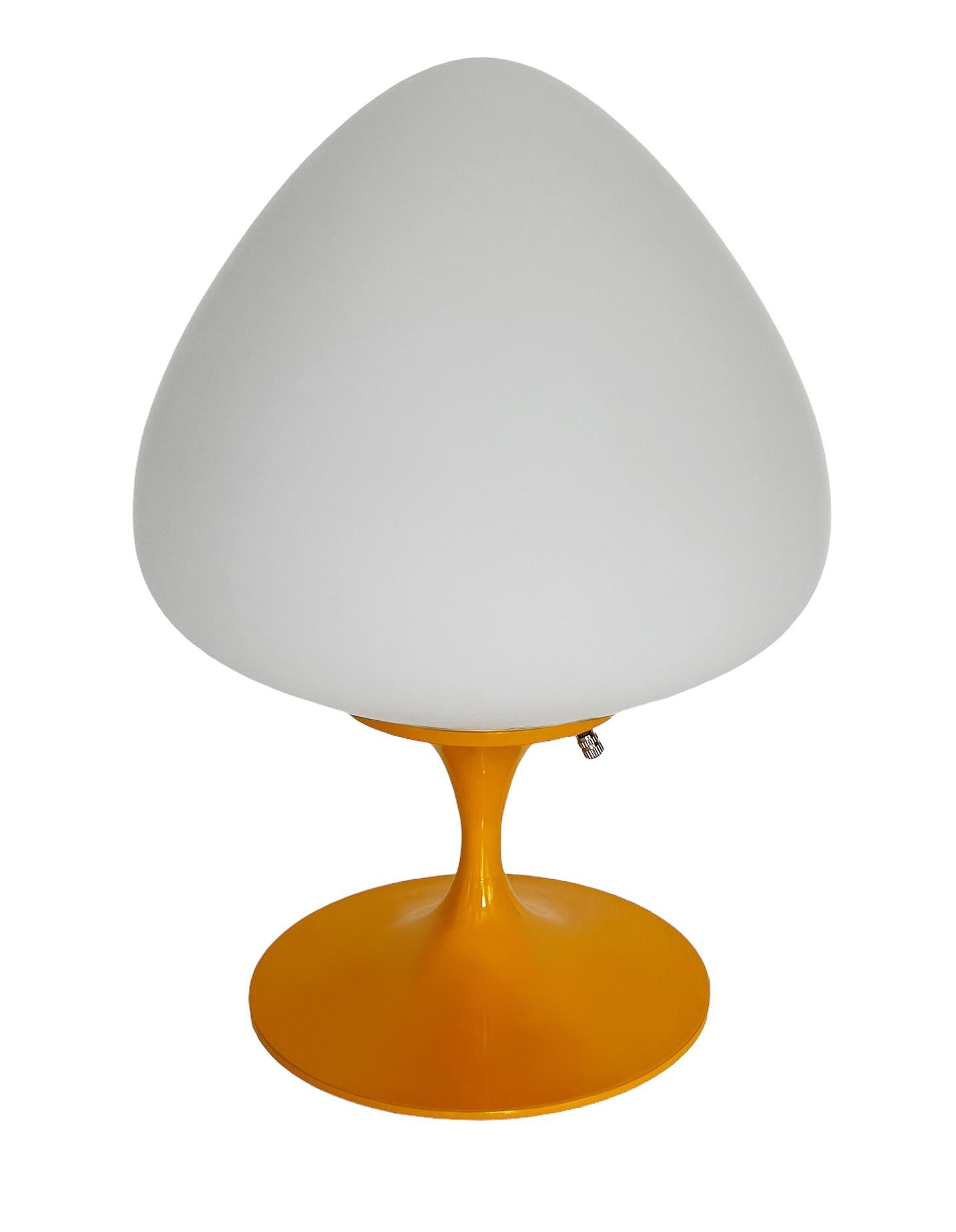 A gorgeous tulip form table lamp, desk lamp or bedside lamp. It features a glossy light orange cast aluminum base with mouth blown frosted white glass shade in an acorn form. It takes one standard bulb up to 100 watts.