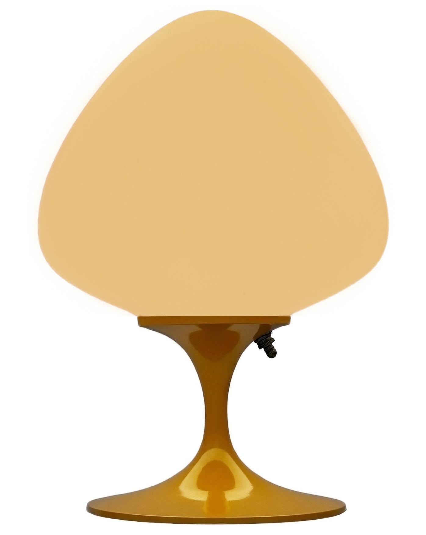 Une magnifique lampe de table, de bureau ou de chevet en forme de tulipe. Whiting se compose d'une base en aluminium moulé jaune moutarde brillant et d'un abat-jour en verre blanc dépoli soufflé à la bouche en forme de gland. Elle accepte une