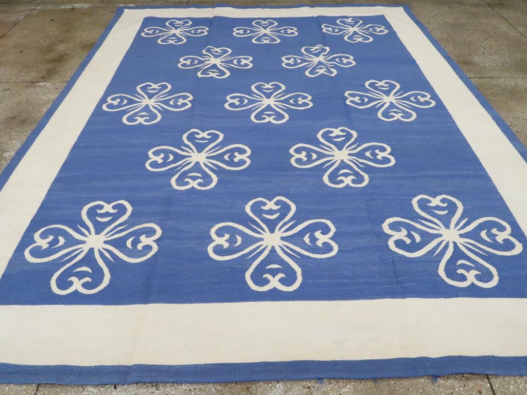 Esta alfombra Kilim turca de tejido plano del siglo XXI, que mide 3,8 m x 4,8 m, presenta una interpretación atrevida y moderna del tejido Kilim tradicional. El llamativo diseño consiste en un campo azul vibrante adornado con una disposición