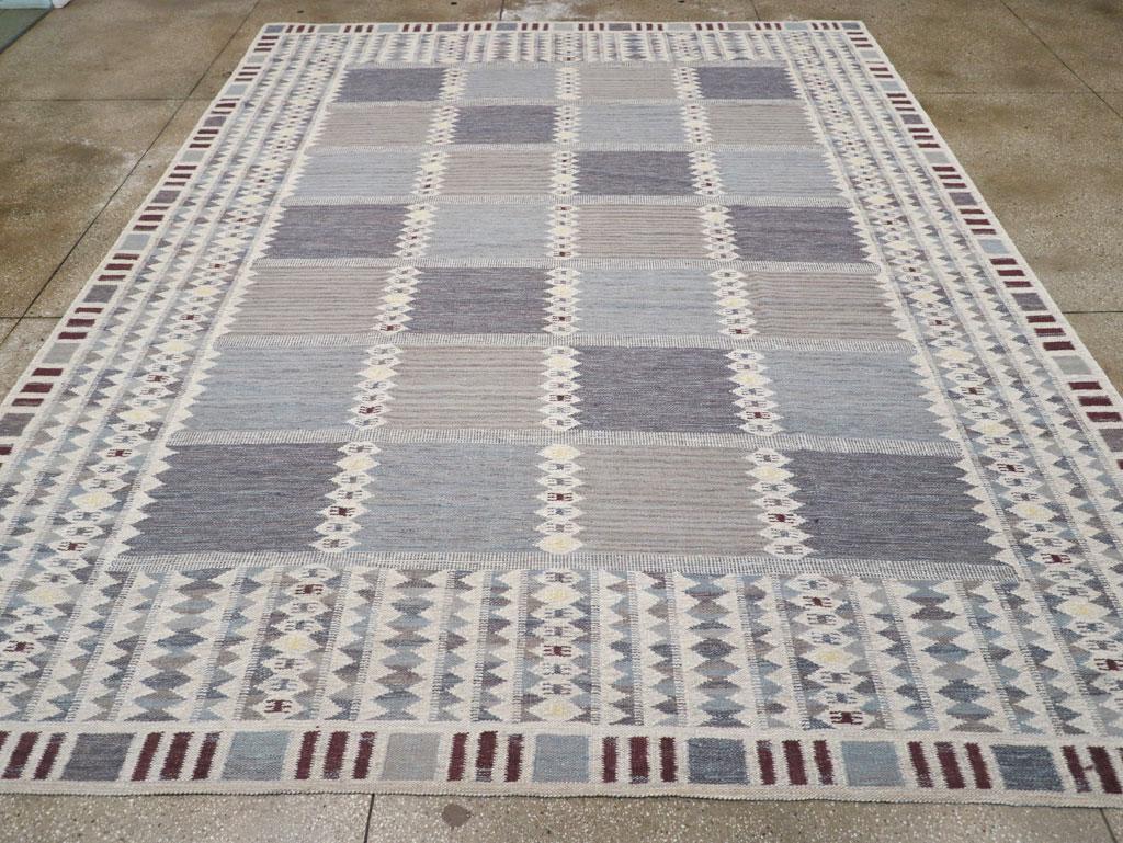 Esta alfombra Kilim turca de tejido plano del siglo XXI, que mide 3 m x 4 m, presenta un llamativo diseño geométrico que refleja la rica tradición del tejido de Anatolia. El campo está adornado con una disposición estructurada de paneles azules y