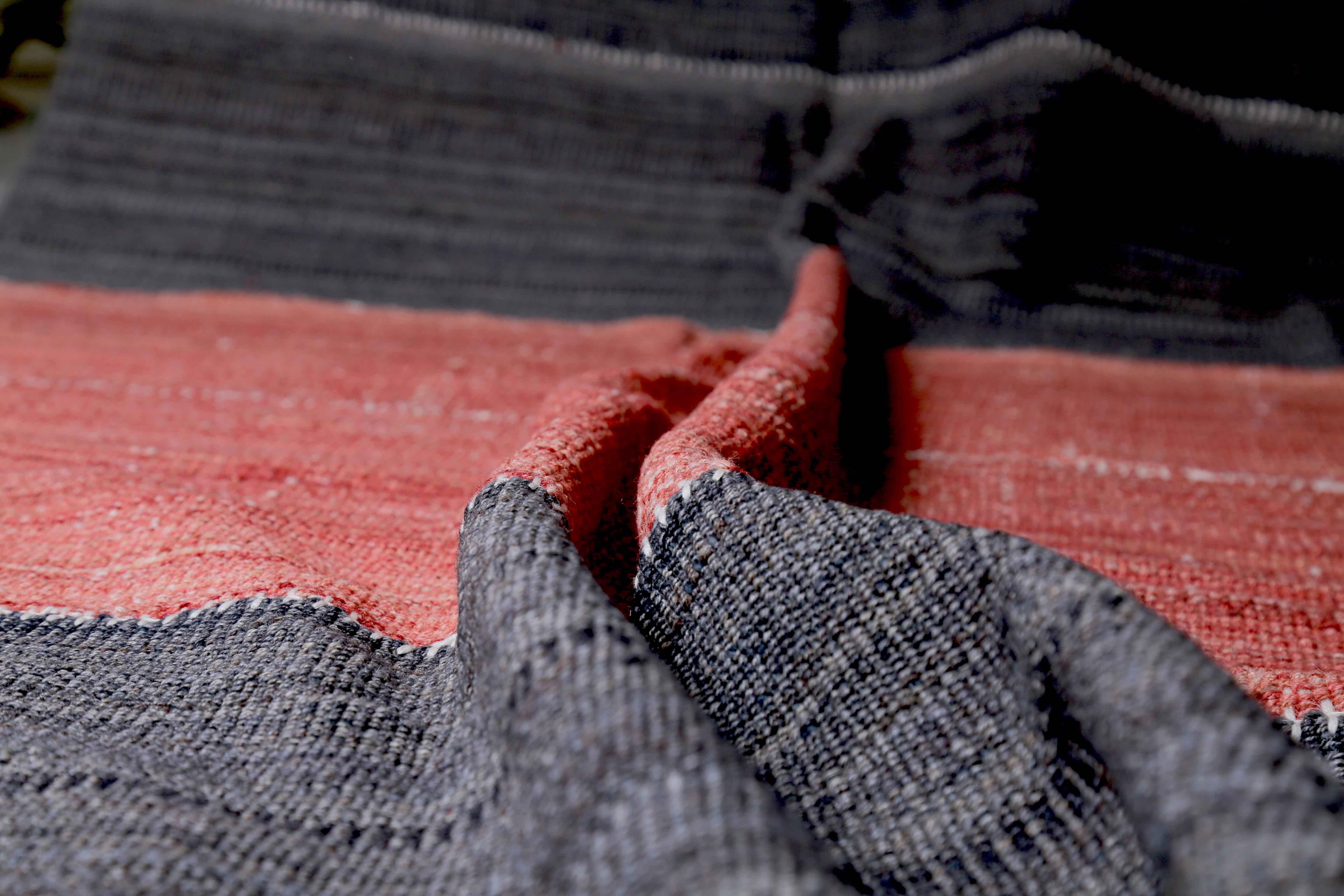 Moderner türkischer Teppich, handgewebt aus feinster Schafwolle und gefärbt mit natürlichen Pflanzenfarben, die für Menschen und Haustiere sicher sind. Es handelt sich um ein traditionelles Kelim-Flachgewebemuster in Rot und Schwarz. Es ist ein