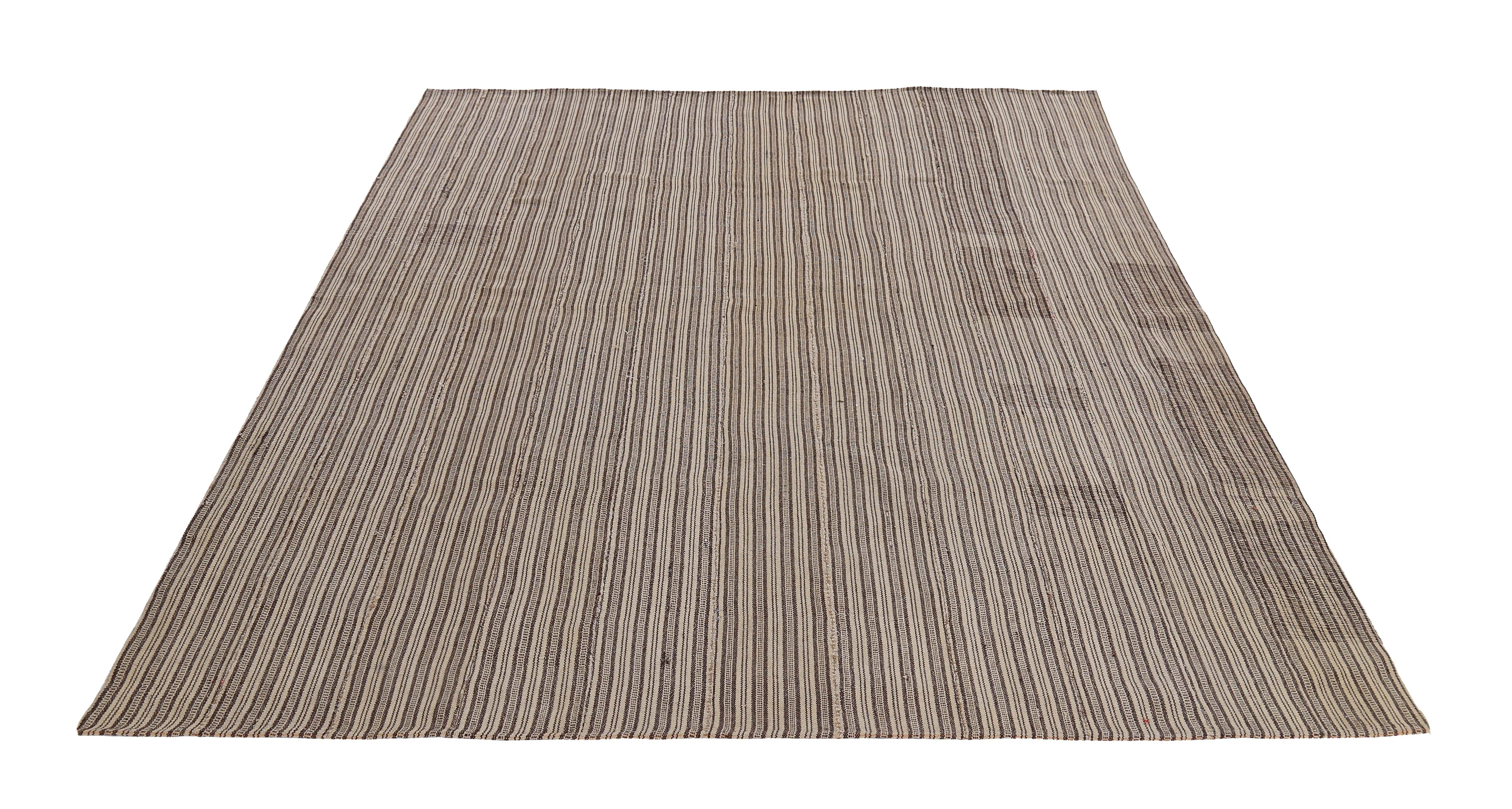 Modern Turkish rug handwoven from the finest sheep’s wool and colored with all-natural vegetable dyes that are safe for humans and pets. It’s a traditional Kilim flat-weave design featuring beige and brown pencil stripes. It’s a stunning piece to