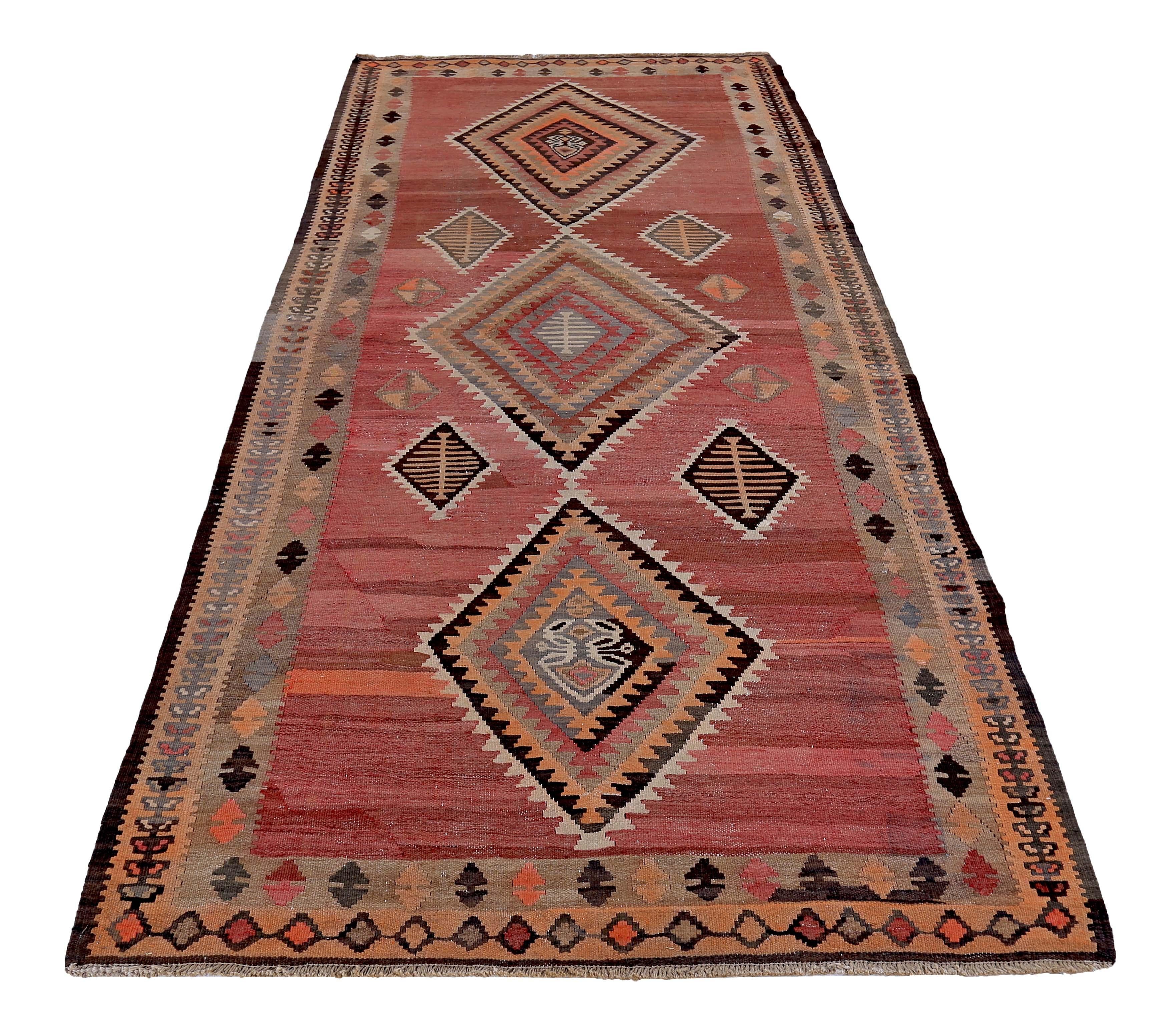 Tappeto turco tessuto a mano con la migliore lana di pecora e colorato con tinture vegetali del tutto naturali e sicure per l'uomo e gli animali domestici. Si tratta di un Kilim tradizionale a trama piatta con motivi tribali a rombi neri, marroni e