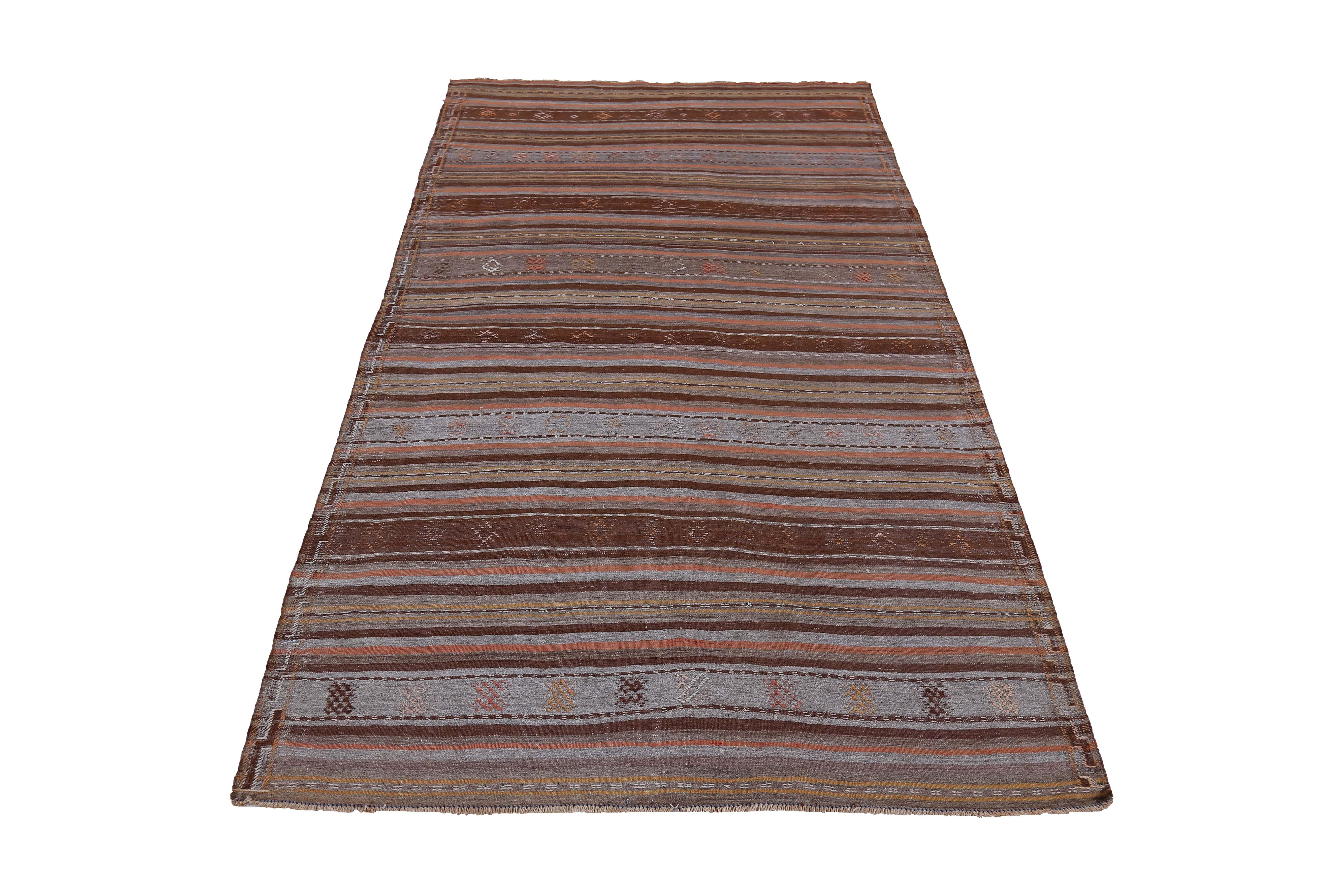 Modern Turkish rug handwoven from the finest sheep’s wool and colored with all-natural vegetable dyes that are safe for humans and pets. It’s a traditional Kilim flat-weave design featuring brown, orange and gray stripes. It’s a stunning piece to