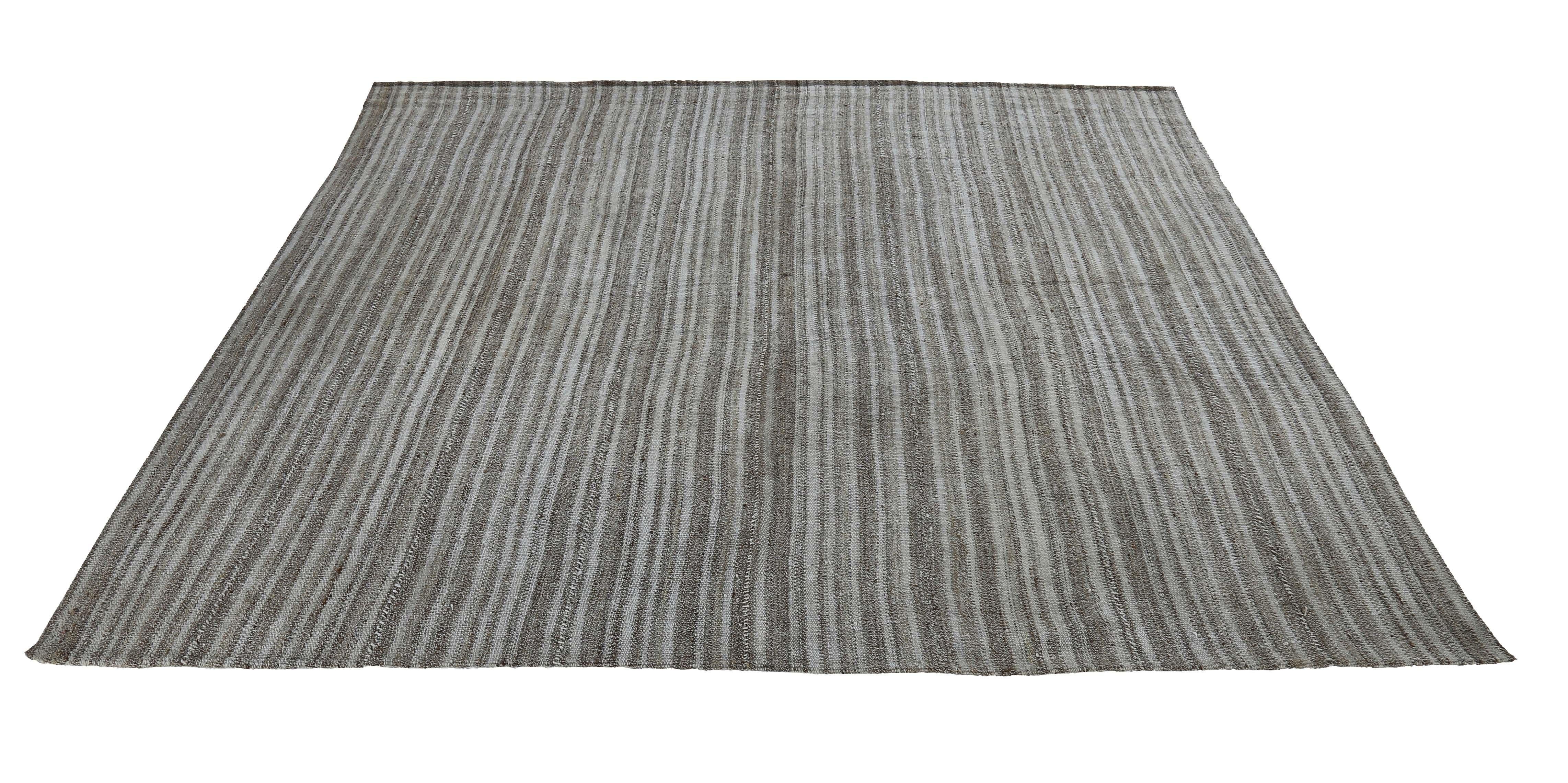 Moderna alfombra turca tejida a mano con la mejor lana de oveja y coloreada con tintes vegetales totalmente naturales, seguros para humanos y mascotas. Se trata de un diseño Kilim tradicional de tejido plano que presenta un campo gris con rayas de